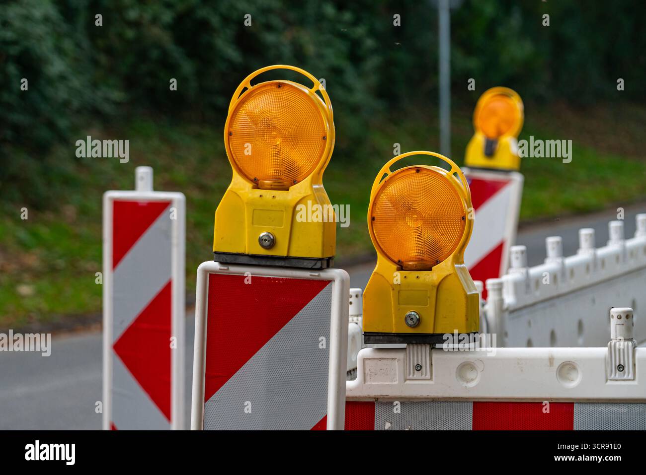 Bright yellow construction lights shine on traffic barriers, signaling ...