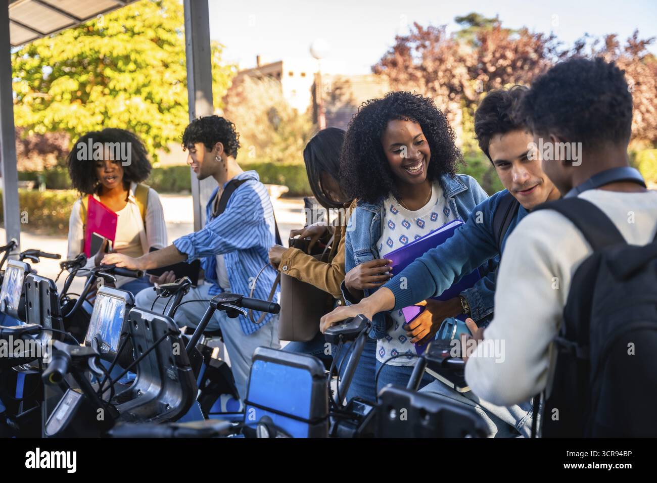 Students Ride Bicycle Group of happy diverse university students activating a shared bicycle ...