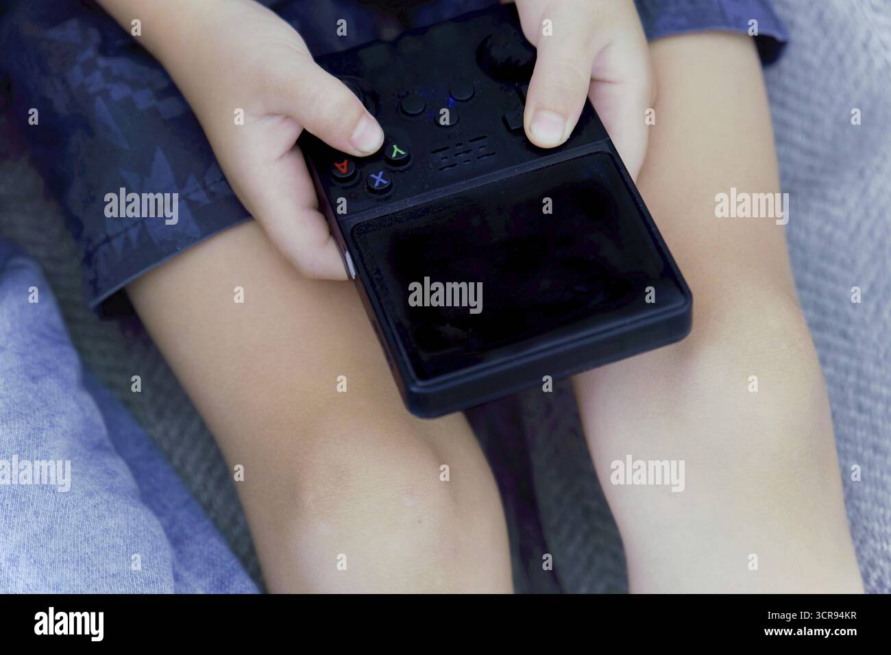 Child's hands holding and playing portable video game console, enjoying entertainment Stock Photo