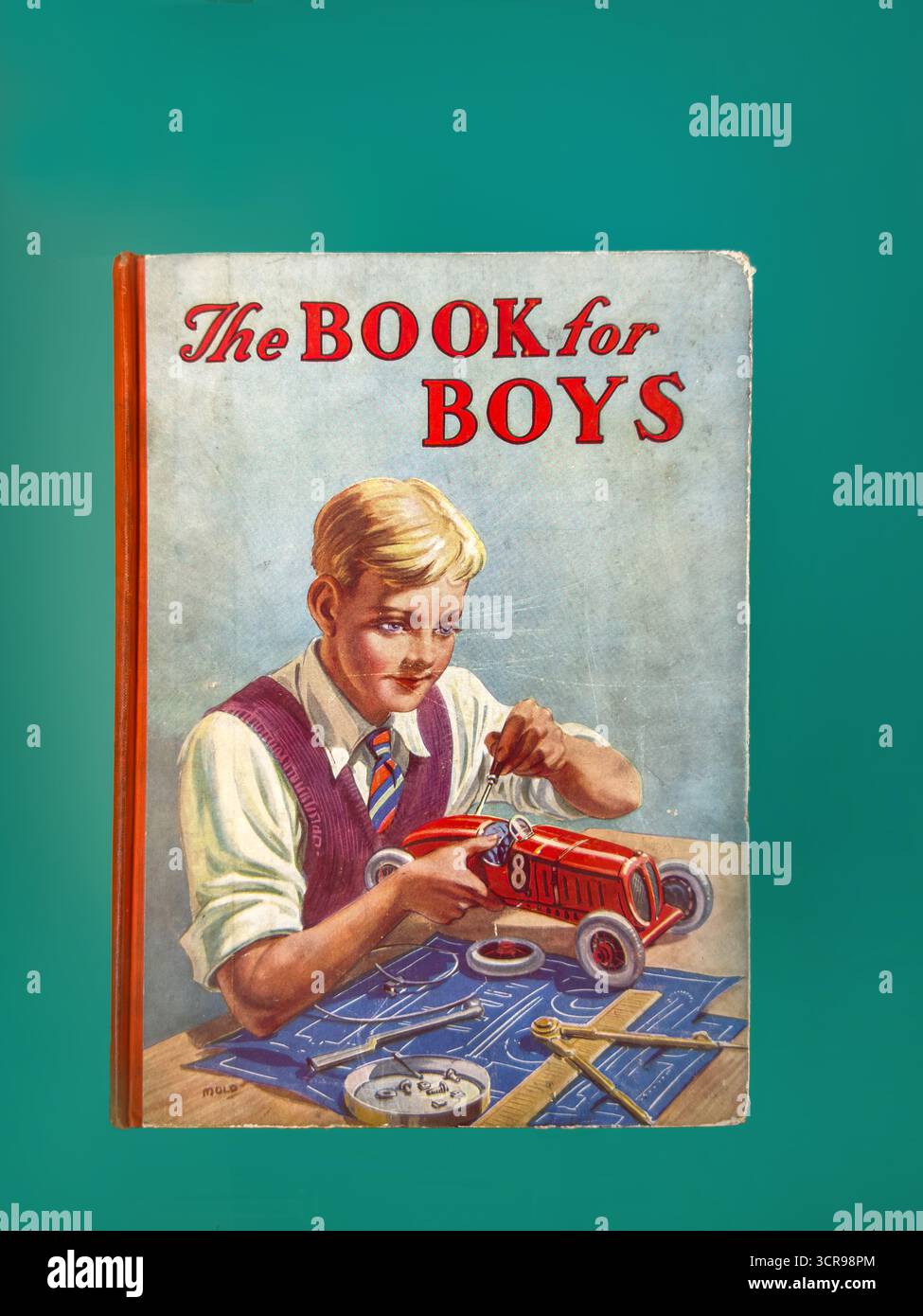 Vintage book cover showing a boy assembling a red toy car, titled 'The Book for Boys', against a teal background - Smartphone Captured Stock Image