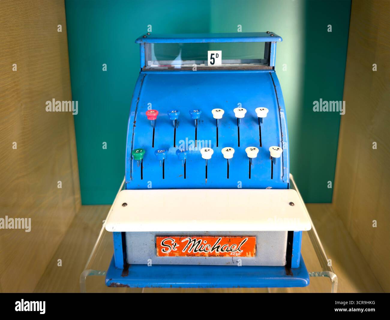 Vintage St. Michael blue metal toy cash register with colourful buttons displayed in a wooden cabinet - Marks & Spencers Uk - Smartphone Captured Stock Image