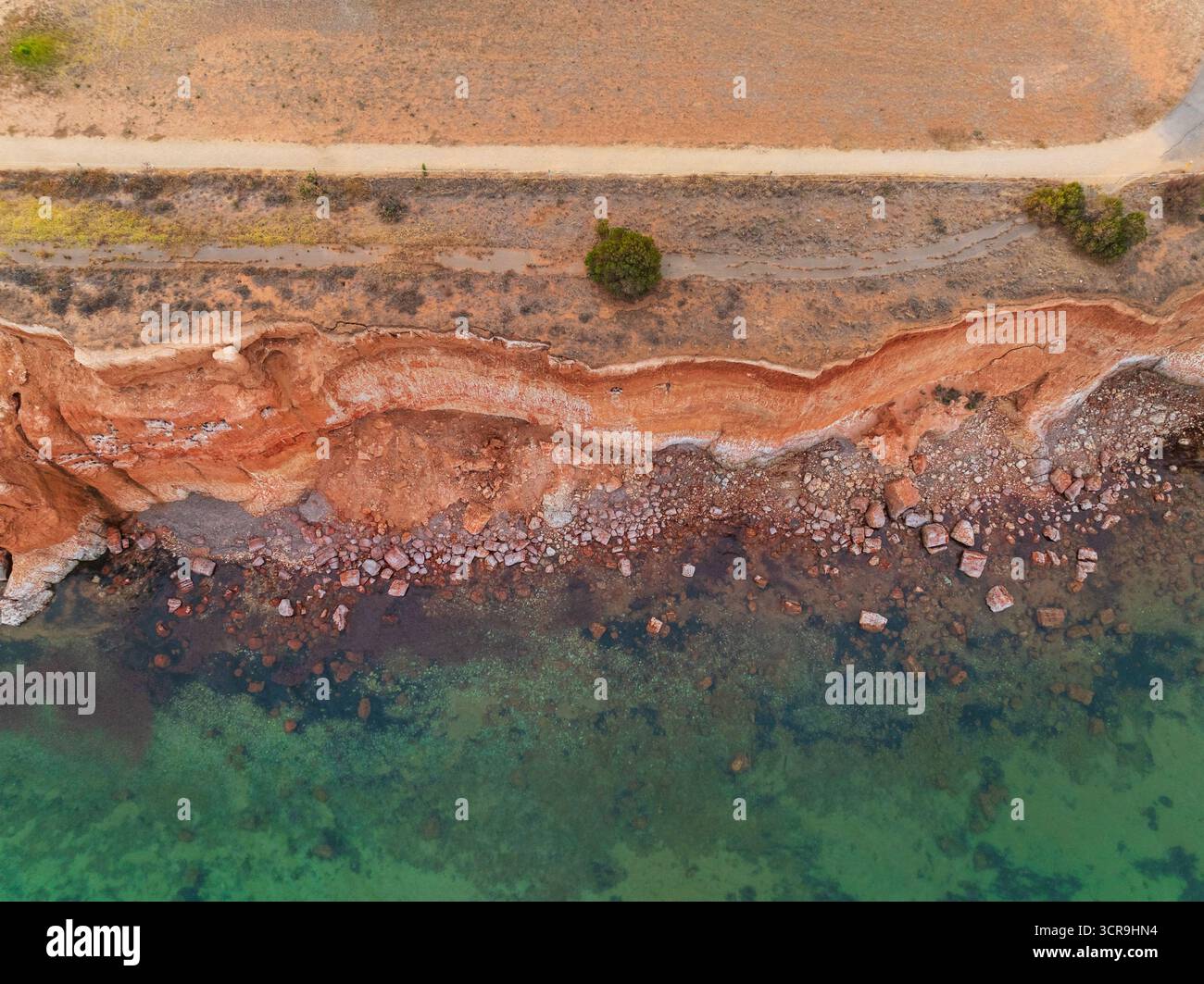 Dross Roxanne Rocks Aerial view of rocks strewn at the base of tall red cliffs along the ...