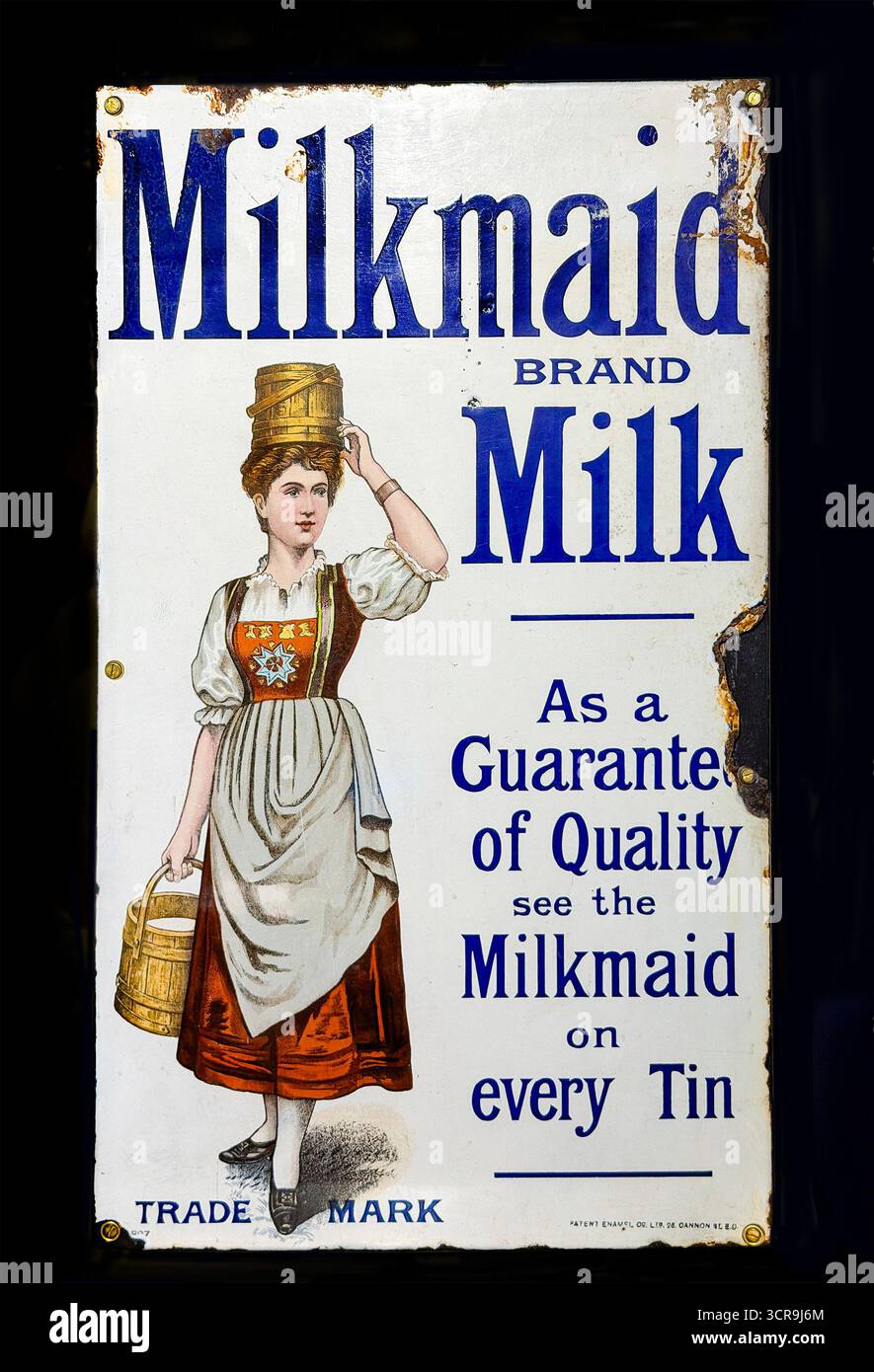 Vintage Milkmaid brand advertisement  on enamel metal sign featuring a woman in traditional attire carrying milk buckets promoting product quality - Smartphone Captured Stock Image