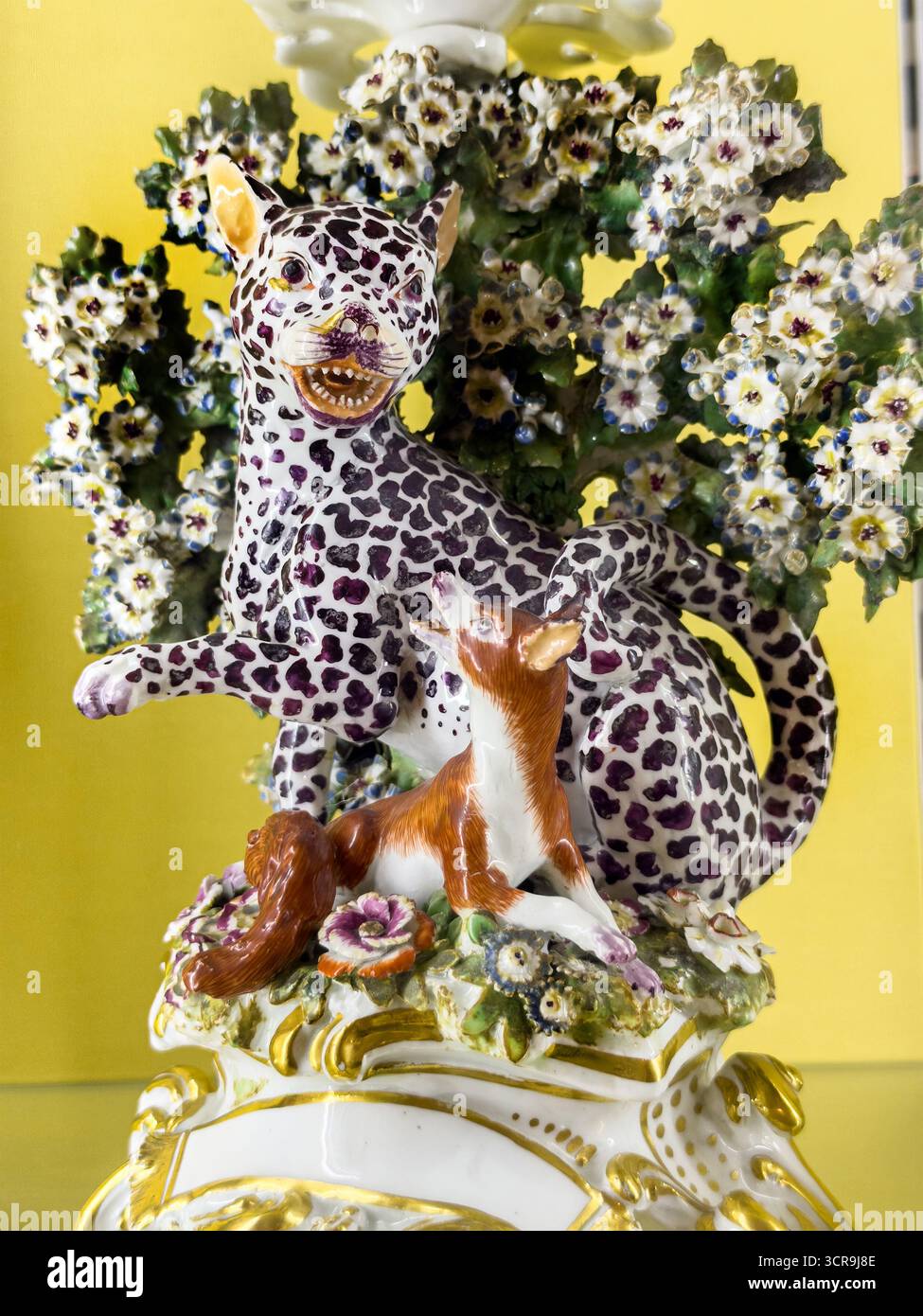 soft paste Porcelain figurine candlestick & floral decorations on yellow background illustrating Aesop’s fables ‘Leopard and the fox' Bowes museum - Smartphone Captured Stock Image