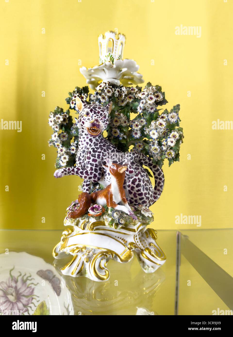 soft paste Porcelain figurine candlestick & floral decorations on yellow background illustrating Aesop’s fables ‘Leopard and the fox' Bowes museum - Smartphone Captured Stock Image