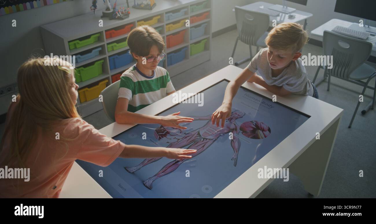 Three Schoolchildren Work Together on Interactive Table Displaying 3D ...