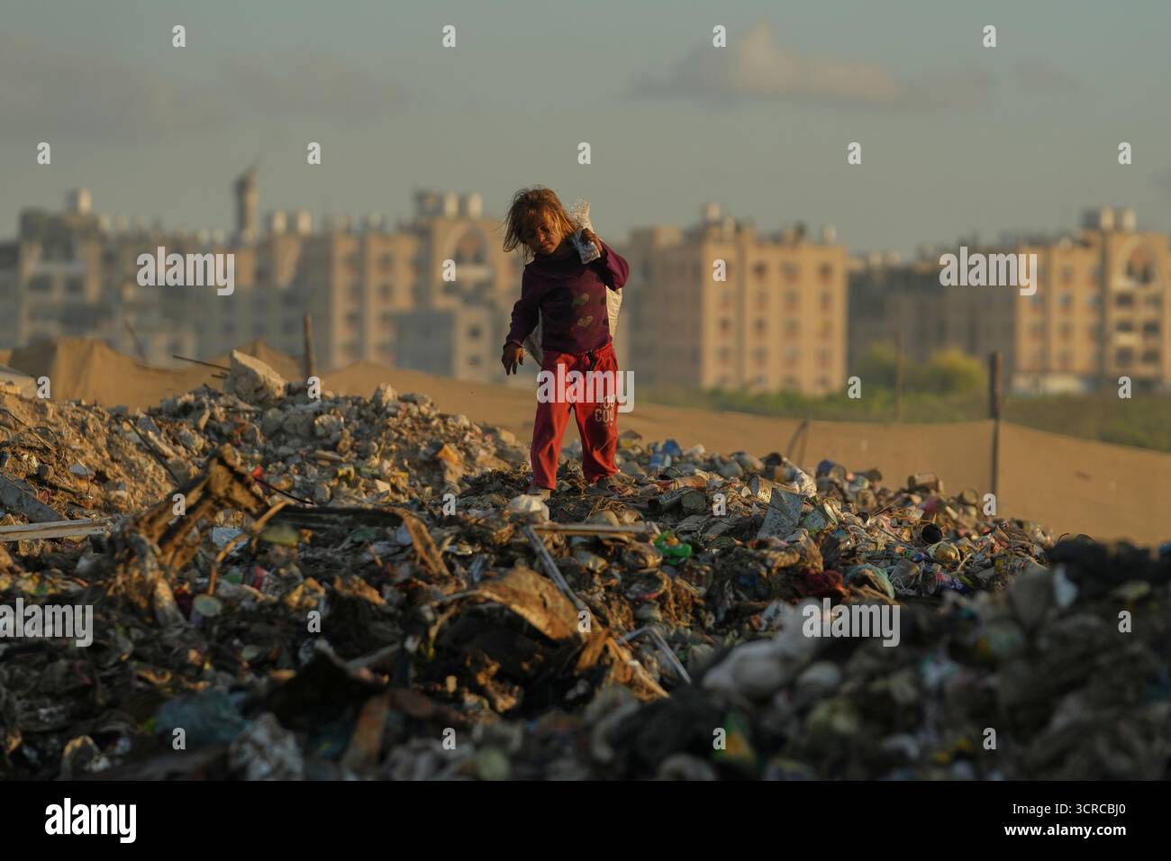 A displaced Palestinian girl searches for firewood and plastic in a ...