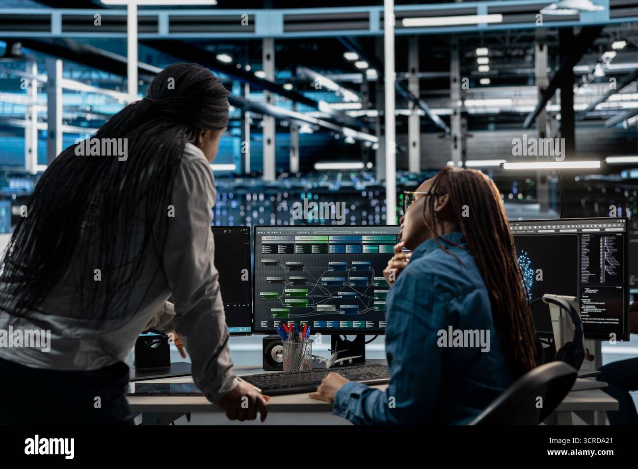 Technicians working together programming in server farm housing infrastructure storing datasets. IT experts collaborating, running code on PC to repair data center racks doing computational operations Stock Photo