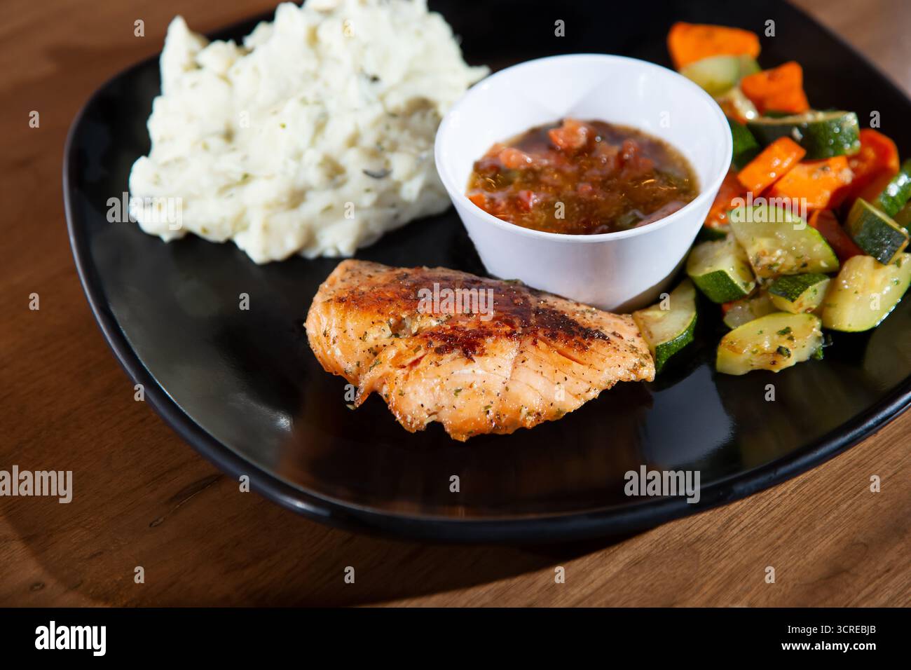 A view of a salmon dinner entree, featuring sautéed vegetables and mashed potatoes. Stock Photo