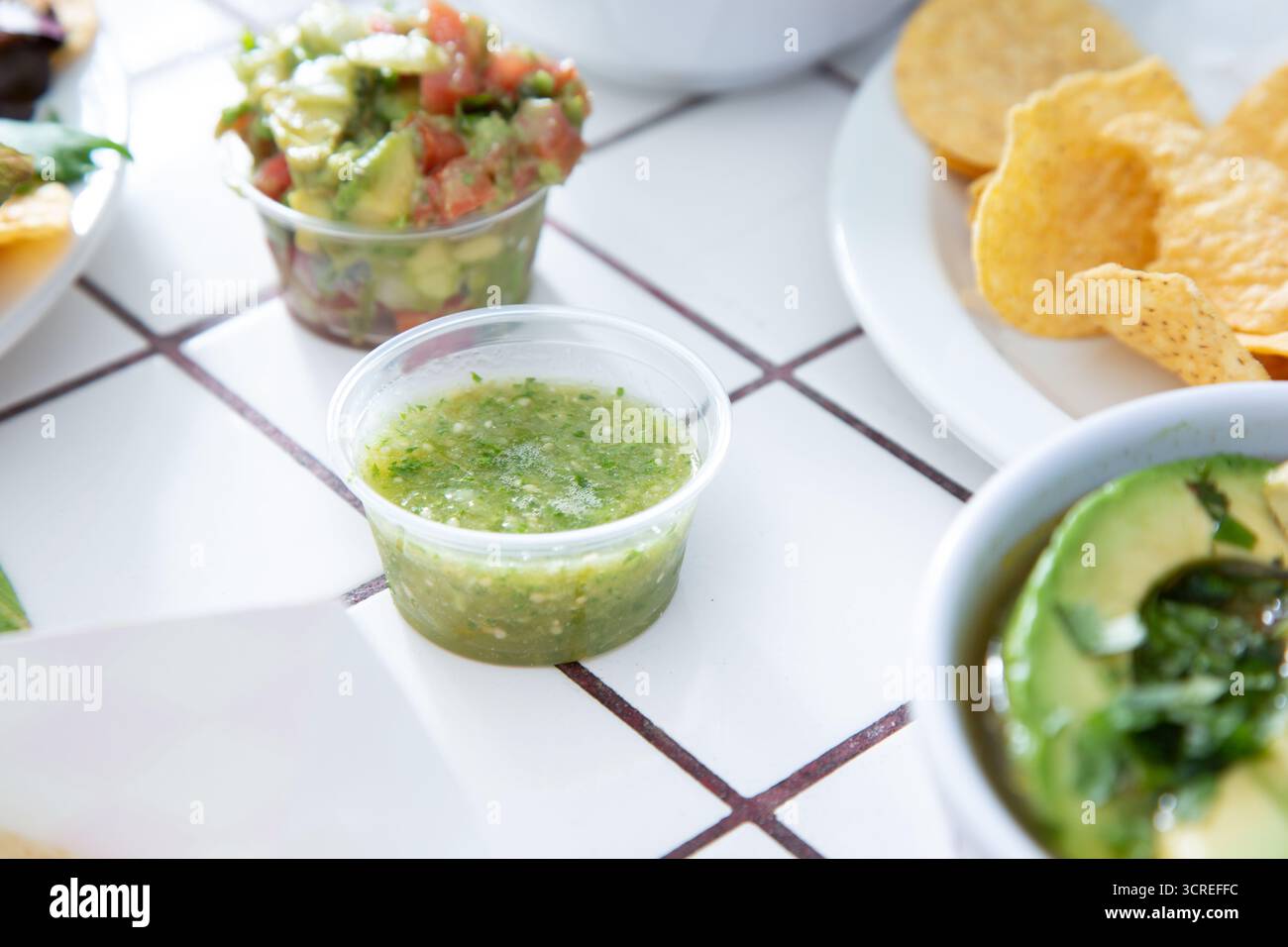 A view of a condiment cup of green salsa, or salsa verde. Stock Photo