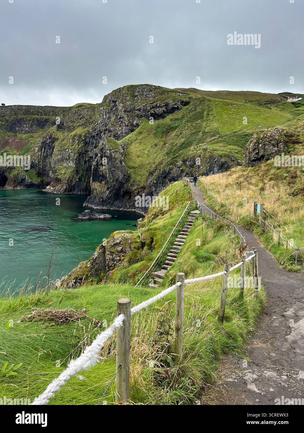 Cliffside walking trail leading down to the turquoise sea at Carrick-a-Rede, County Antrim, Northern Ireland. - Smartphone Captured Stock Image