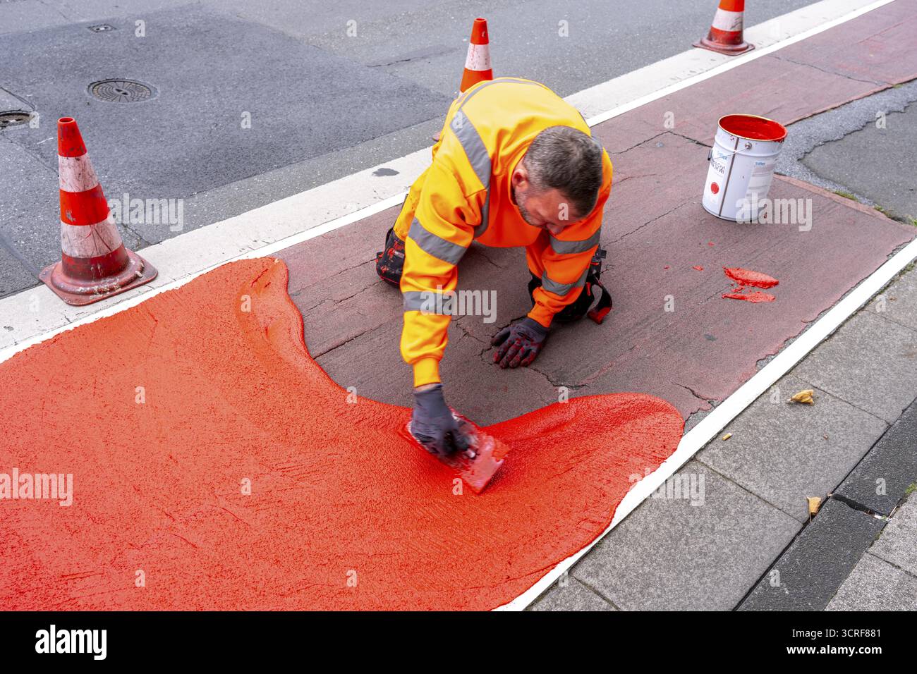 Application of red road surfacing on a cycle lane, inner-city road, so-called cold plastic surfacing, in the colour traffic red, RAL3020, the coloured Stock Photo