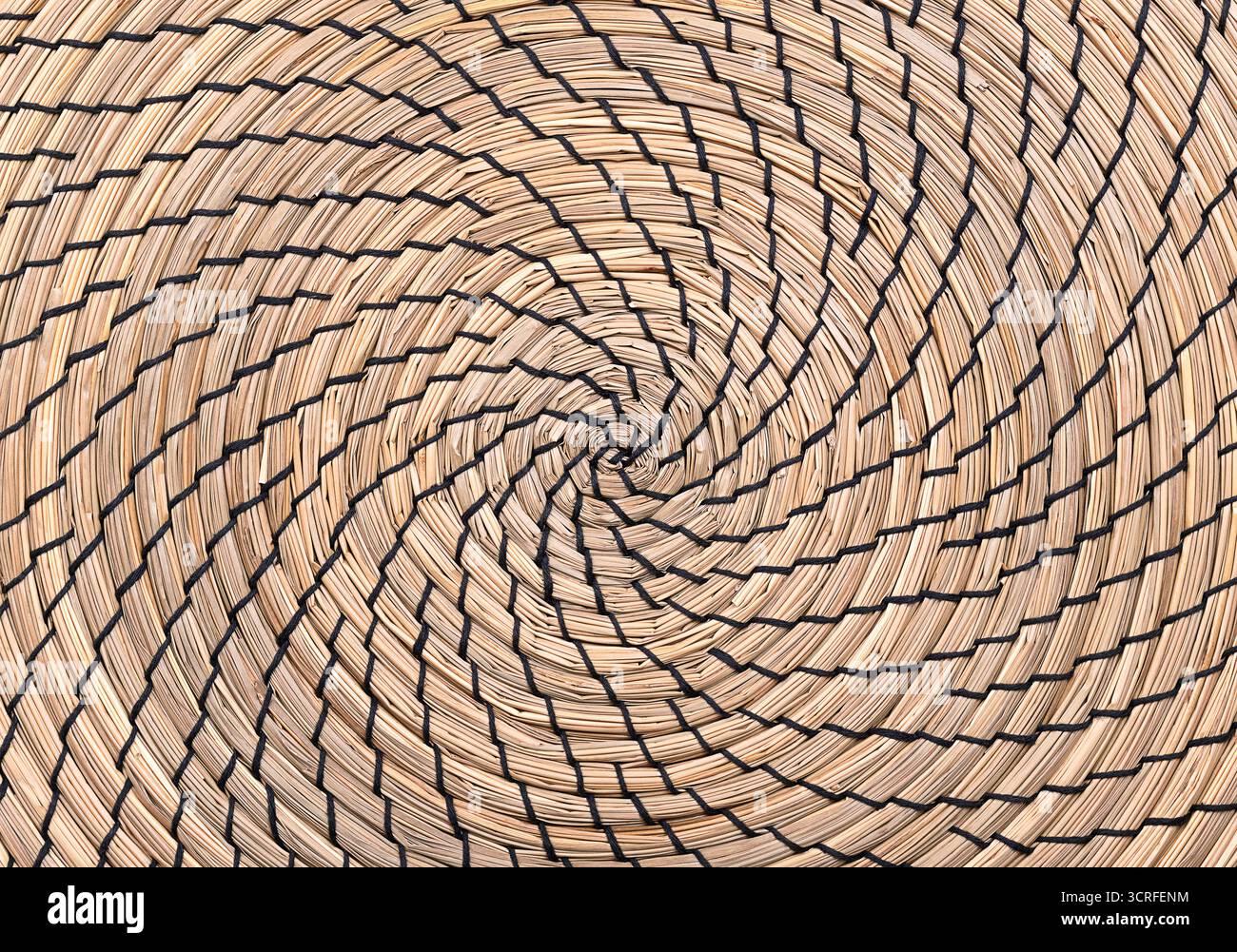 Seagrass place mat, clockwise wound in the shape of a spiral, and sewn with black thread. Natural and organic underlay, made of sedge. Stock Photo