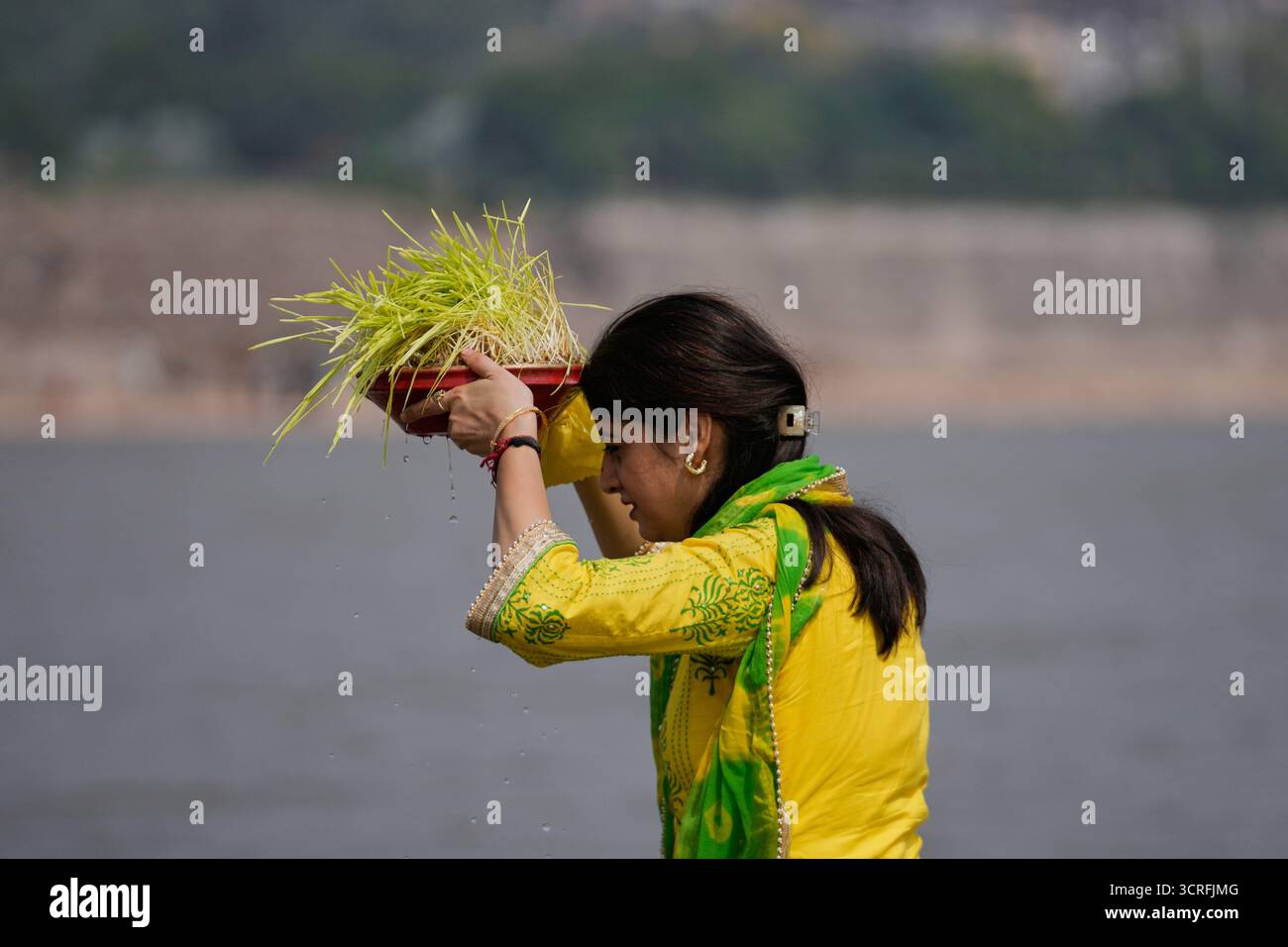 A Hindu devotee performs rituals with barley saplings in the River Tawi ...