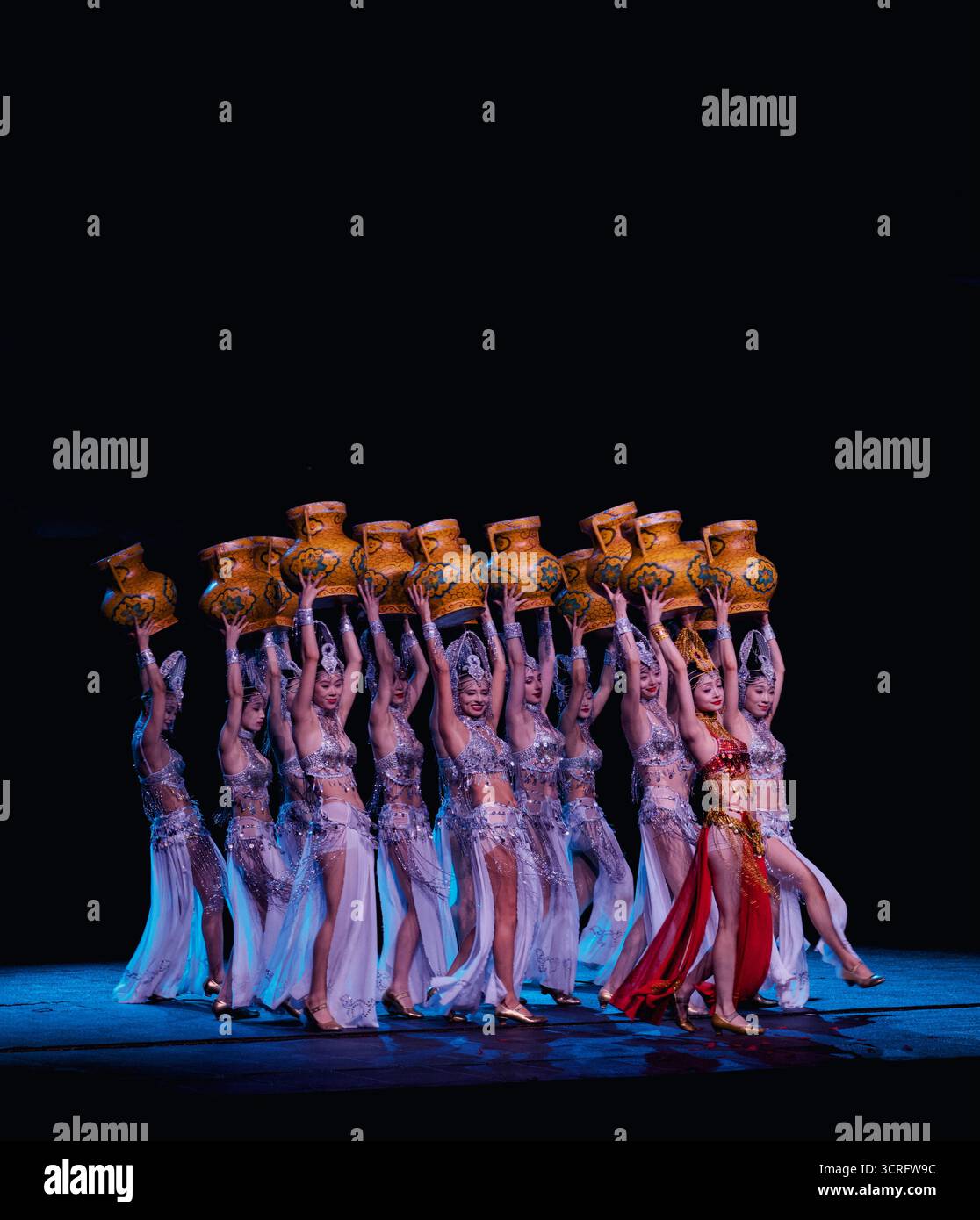 Belly dancers are elegantly holding vases while performing on a stage Stock Photo