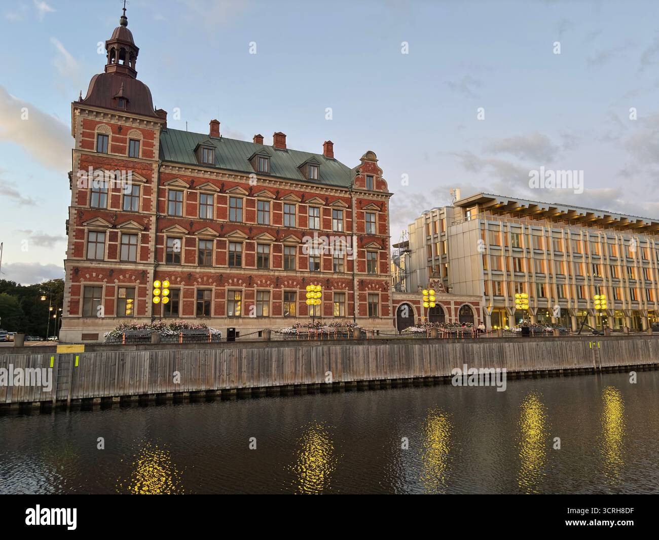 Sunset over iconic buildings in Landskrona Sweden with harbor structures and coastal skyline reflections. Stock Photo