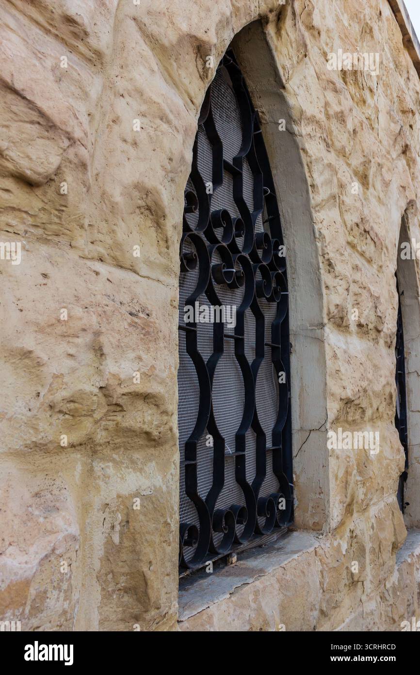 Rustic Stone Wall With Arched Window And Decorative Iron Bars On ...
