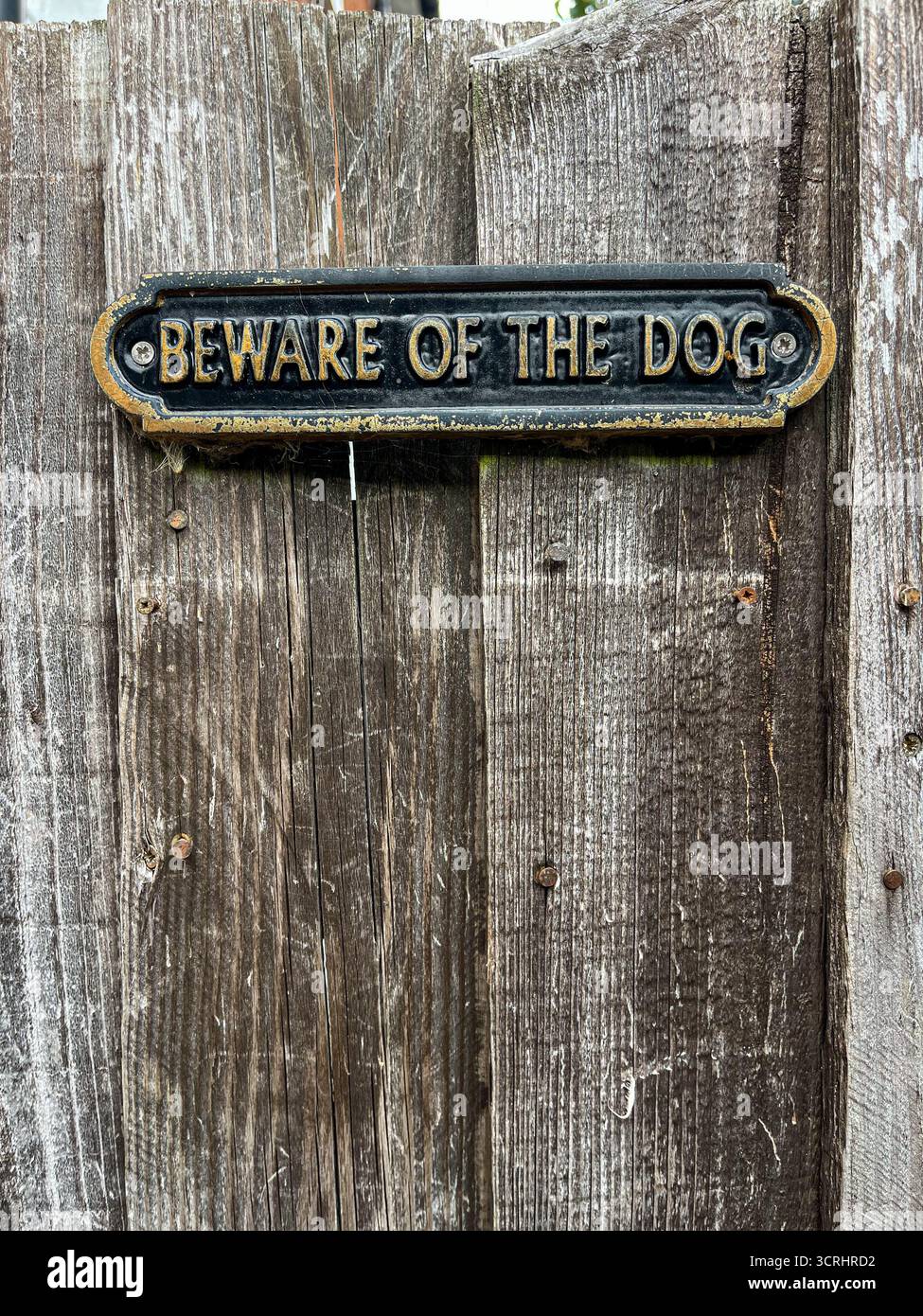A metal sign on a wooden gate with the inscription: ‘Beware of the Dog’ in England. - Smartphone Captured Stock Image