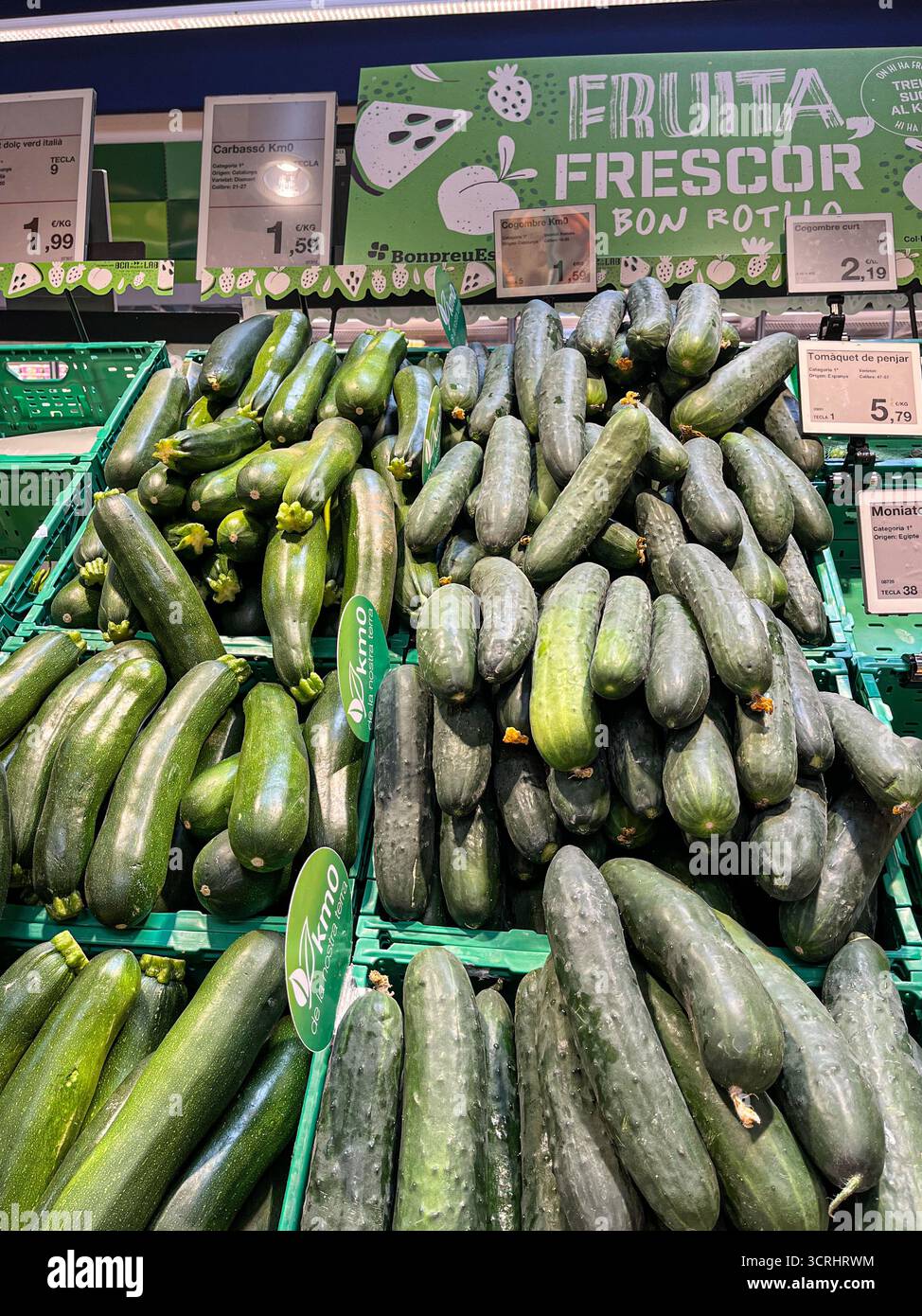 Supermarket Esclat, Spain, Catalonia, Tossa de mar. 14.08.2025. Produce section (aisle) with fresh cucumbers and zucchini in a supermarket. - Smartphone Captured Stock Image