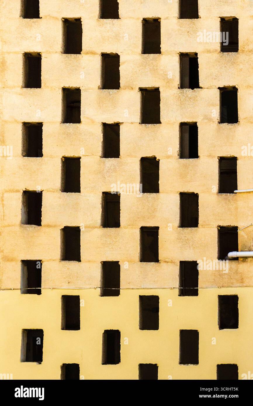 Sunlit Geometric Wall With Recessed Rectangular Windows In A Regular Grid Pattern Stock Photo