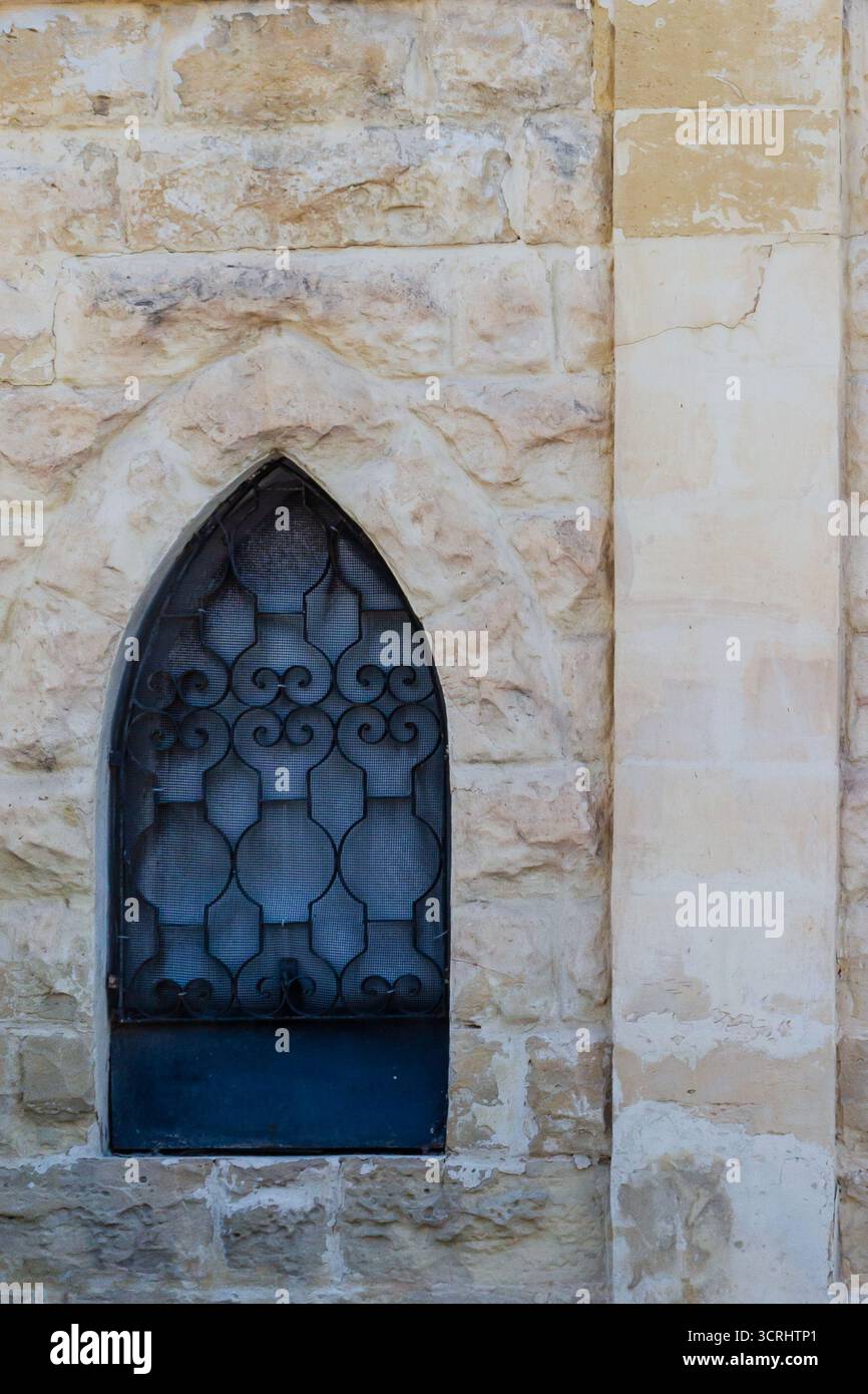 Rustic Stone Wall With Arched Window And Decorative Iron Bars On ...