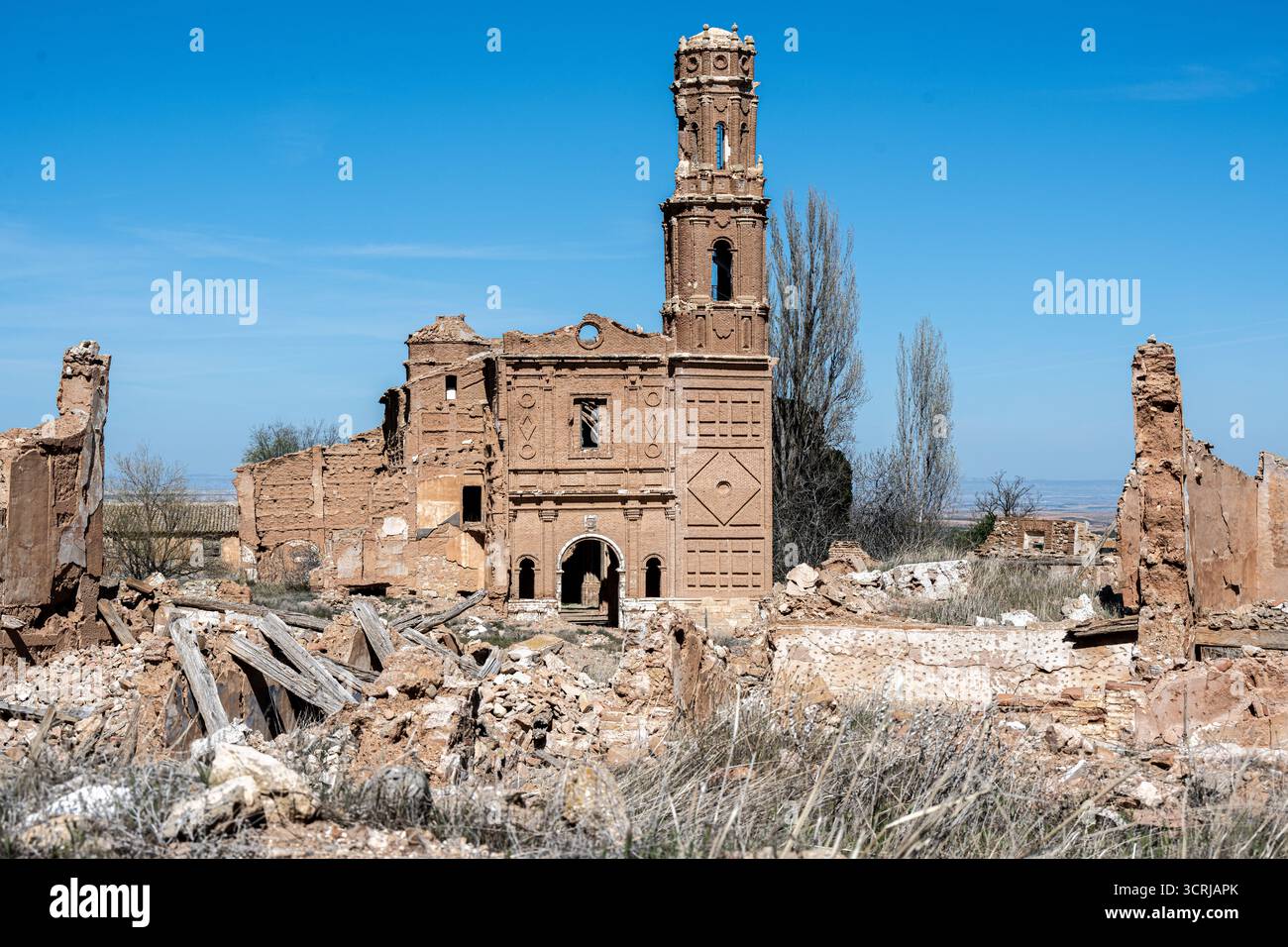 A ruined building with a tall tower, surrounded by debris and overgrown ...