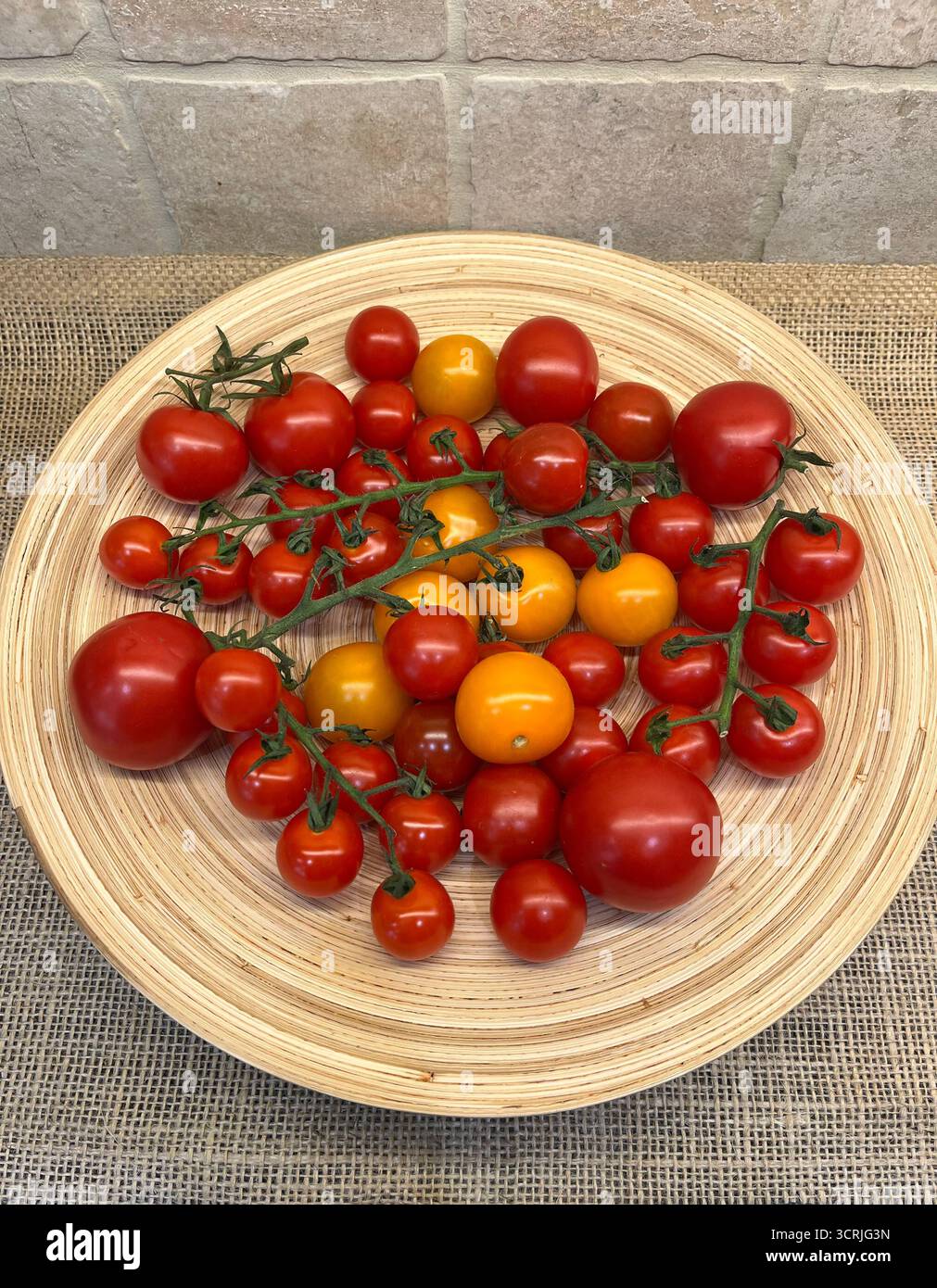 Cherry tomatoes yellow and red on branches on a bamboo plate - Smartphone Captured Stock Image