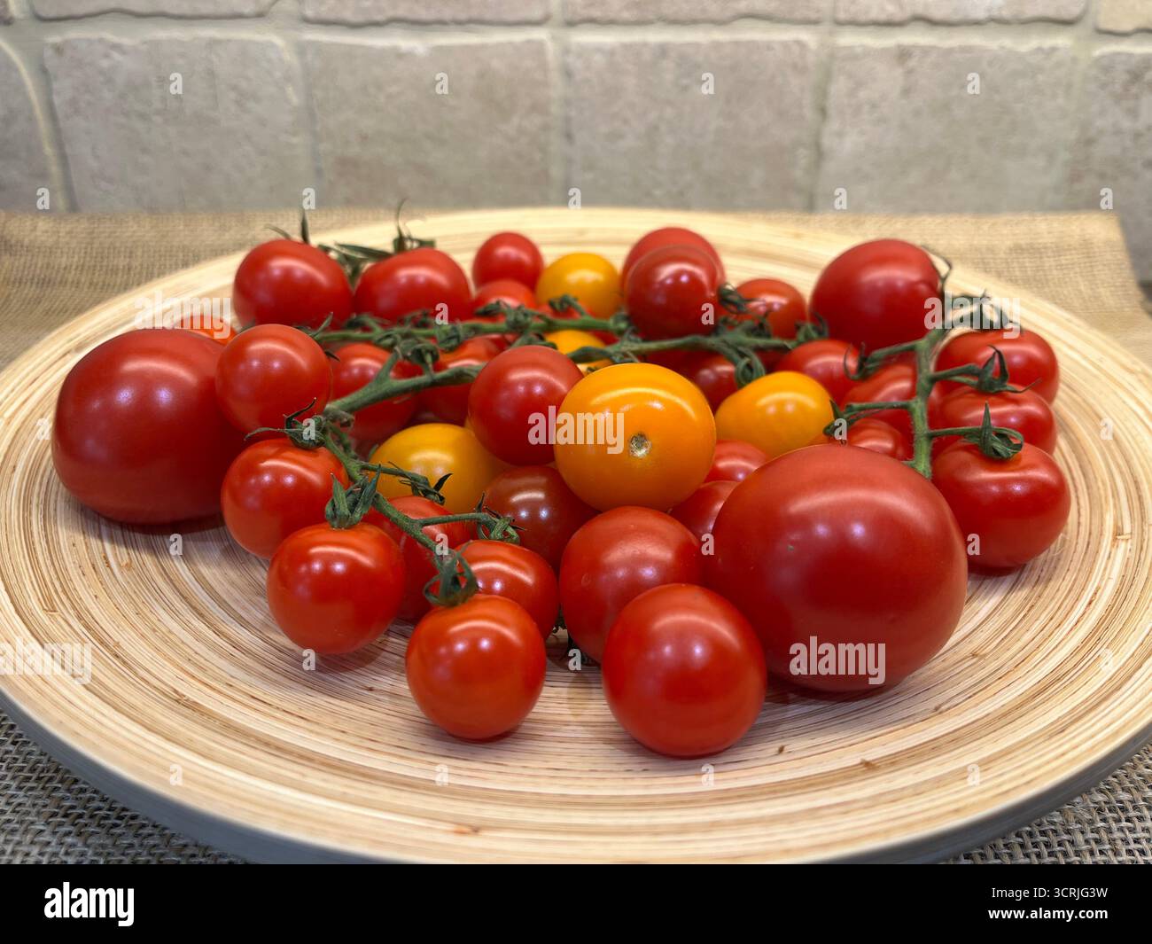 Cherry tomatoes yellow and red on branches on a bamboo plate - Smartphone Captured Stock Image
