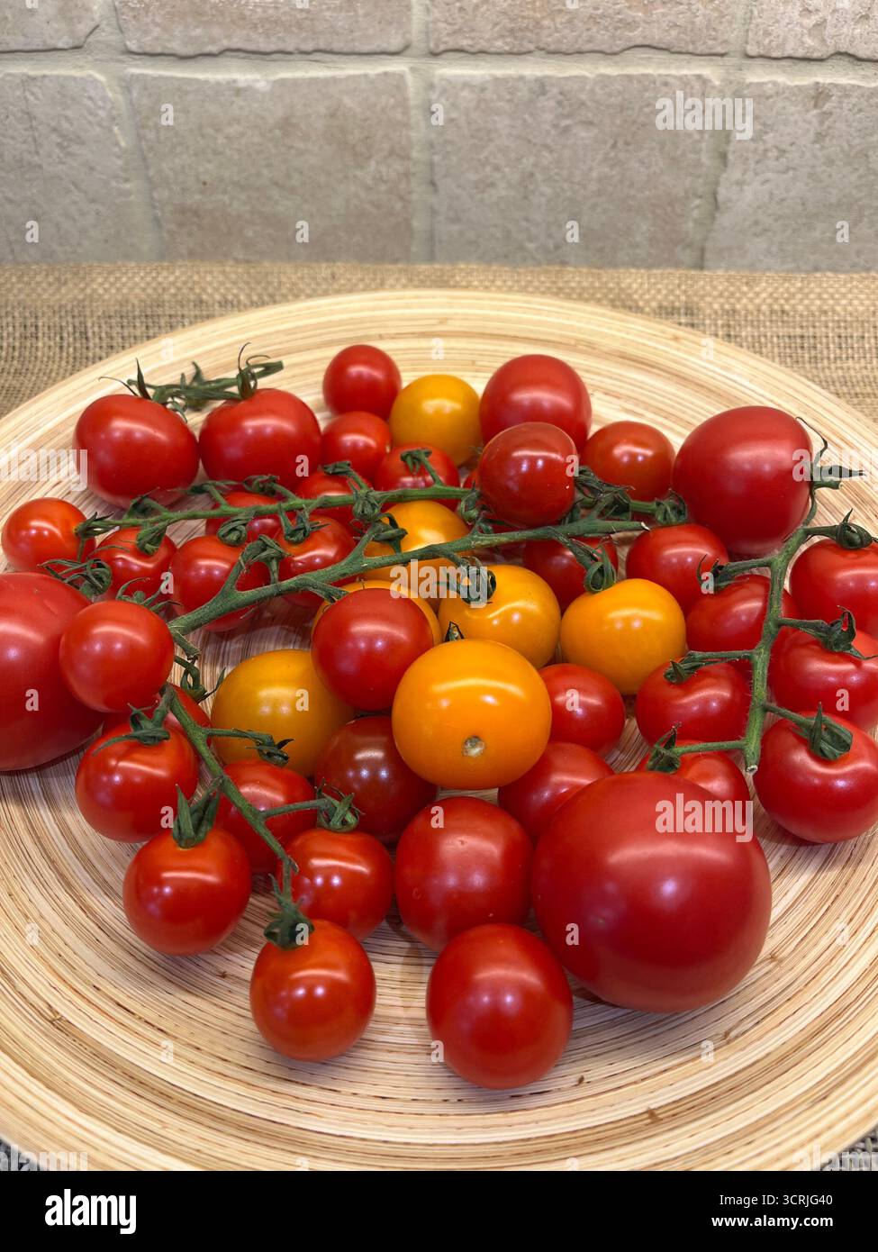 Cherry tomatoes yellow and red on branches on a bamboo plate - Smartphone Captured Stock Image