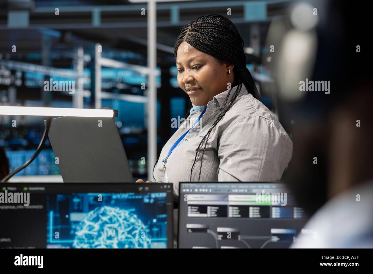 Smiling technician in data center uses AI technology for machine learning workloads. Happy server hub facility worker using artificial intelligence to perform demanding computing tasks Stock Photo