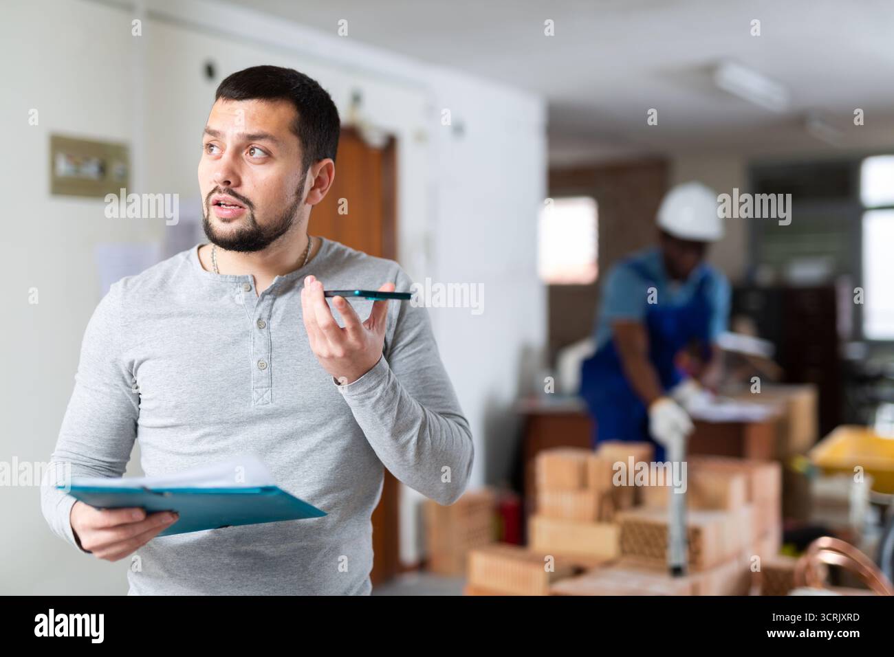 Construction manager with paper folder having telephone conversation Stock Photo