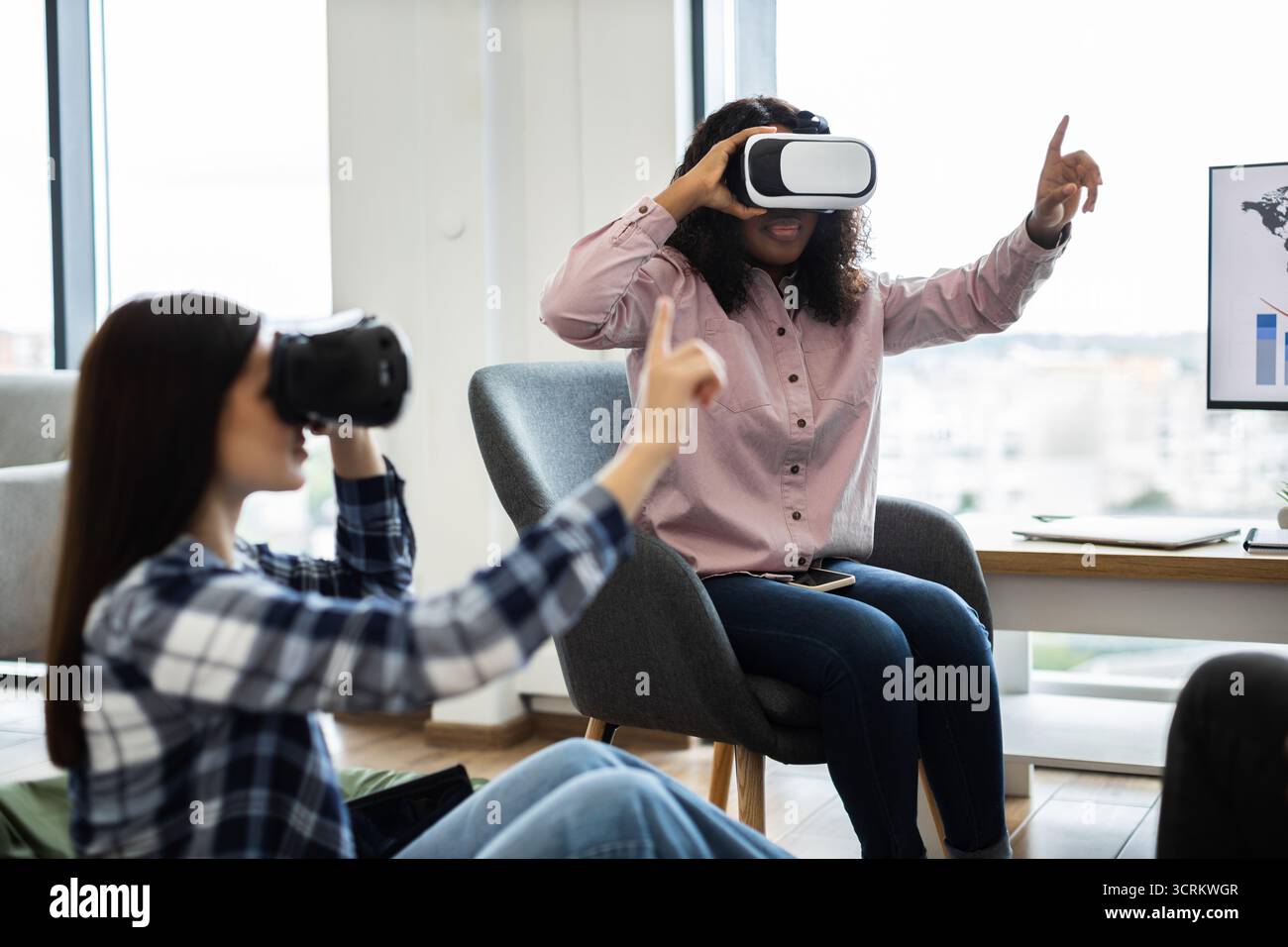 Women using virtual reality glasses in modern workspace environment Stock Photo