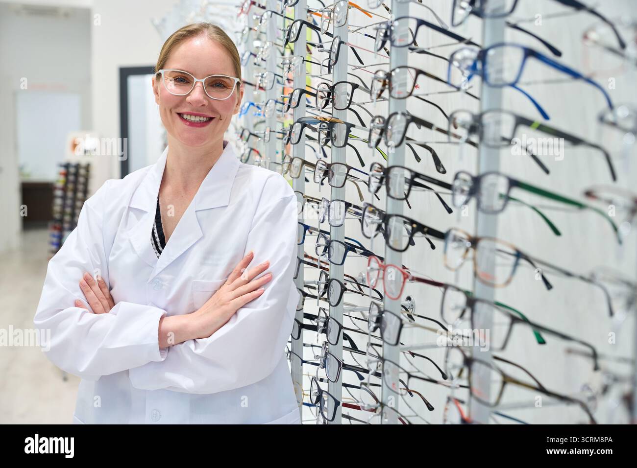 Optometrist woman smiling, standing in optical store Stock Photo