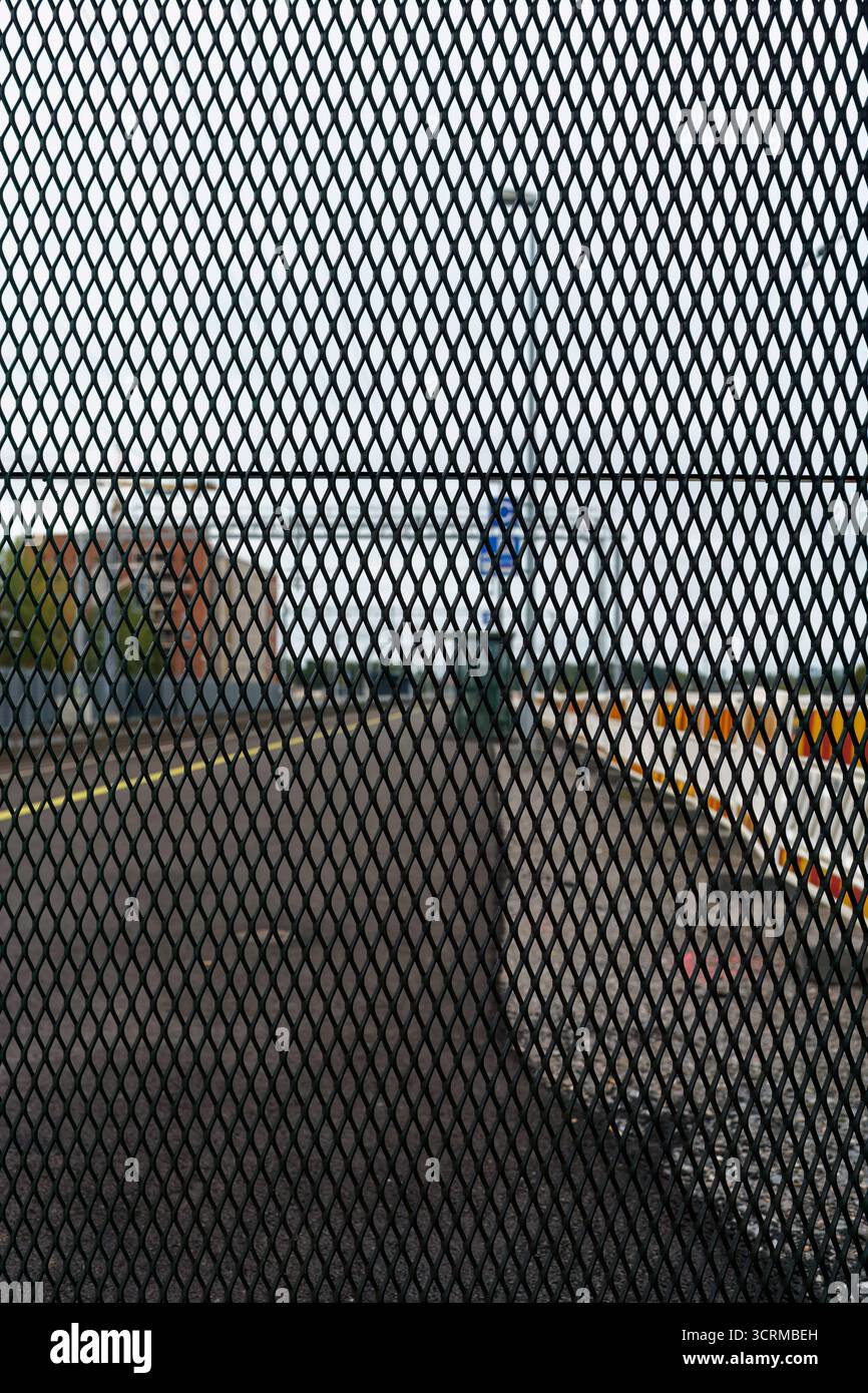 Train station platform viewed through a steel grille mesh. Stock Photo