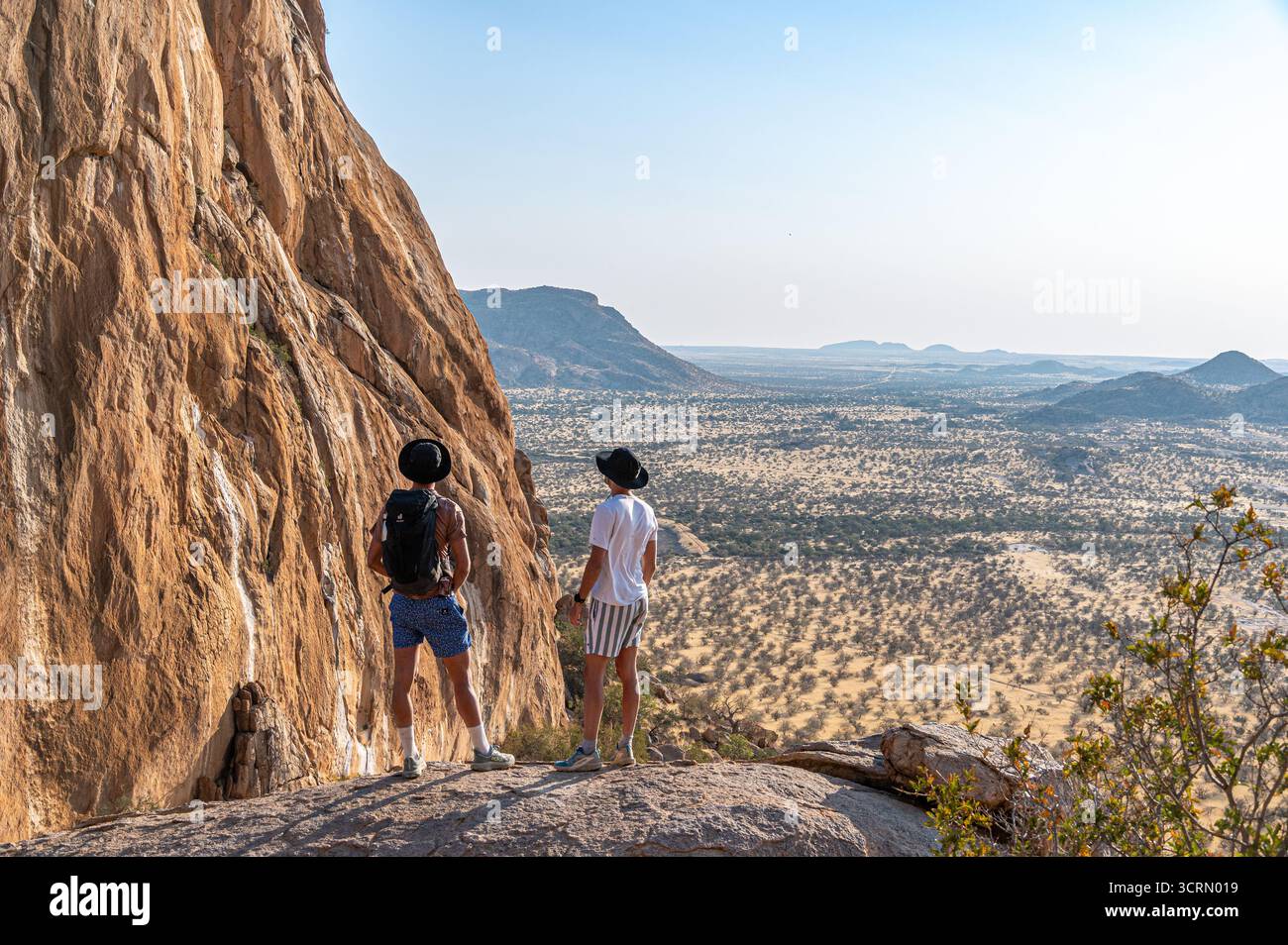 Namibia Cliffs Two hikers standing on rocky cliff edge at Erongo, backpacks resting ...