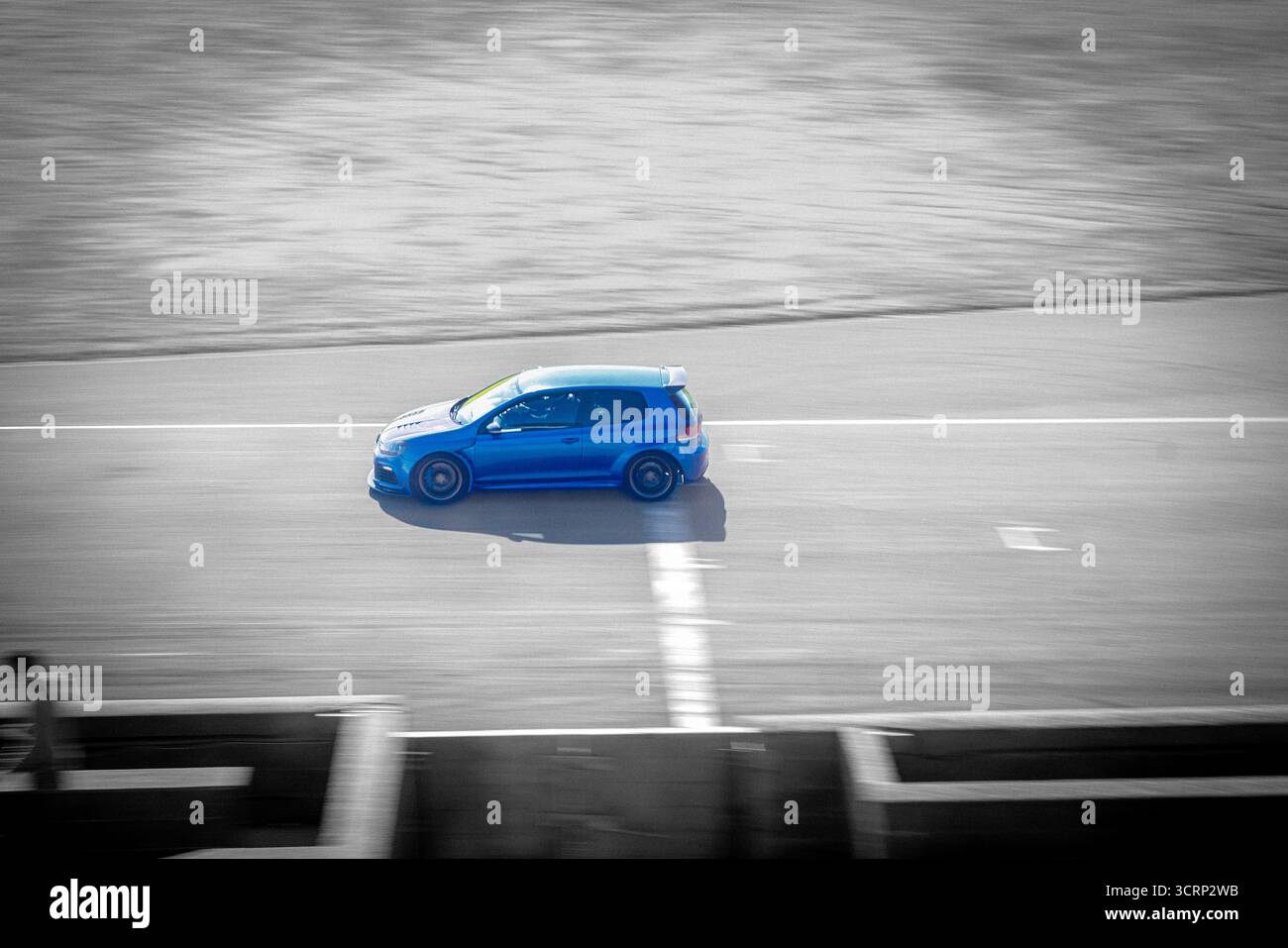 Blue Volkswagen Golf in selective color against black and white background, automotive close-up, urban scene, photography highlighting detail design Stock Photo