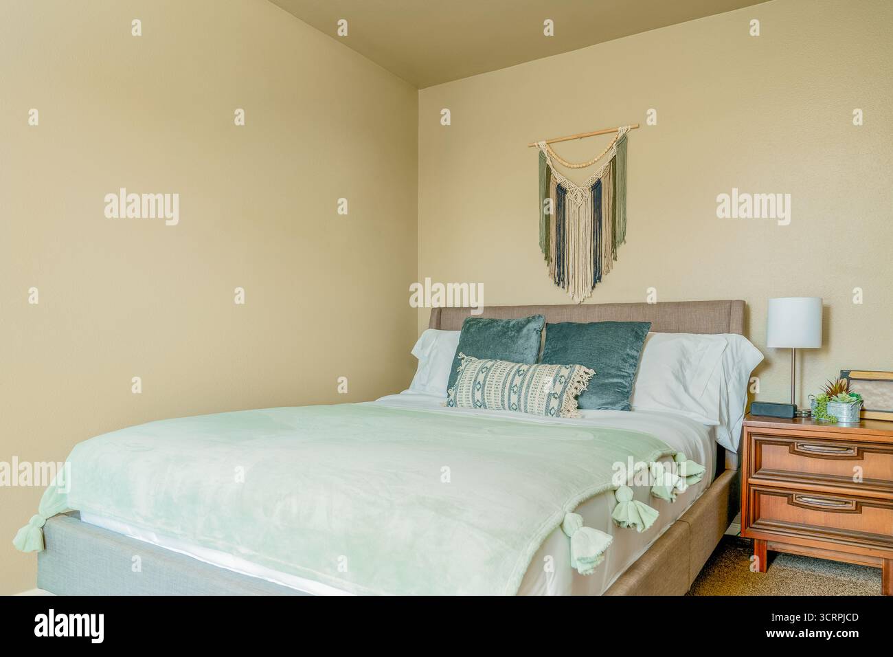 Bedroom blue green pillows, bed, nightstand, macrame wall art, desert southwest theme Stock Photo
