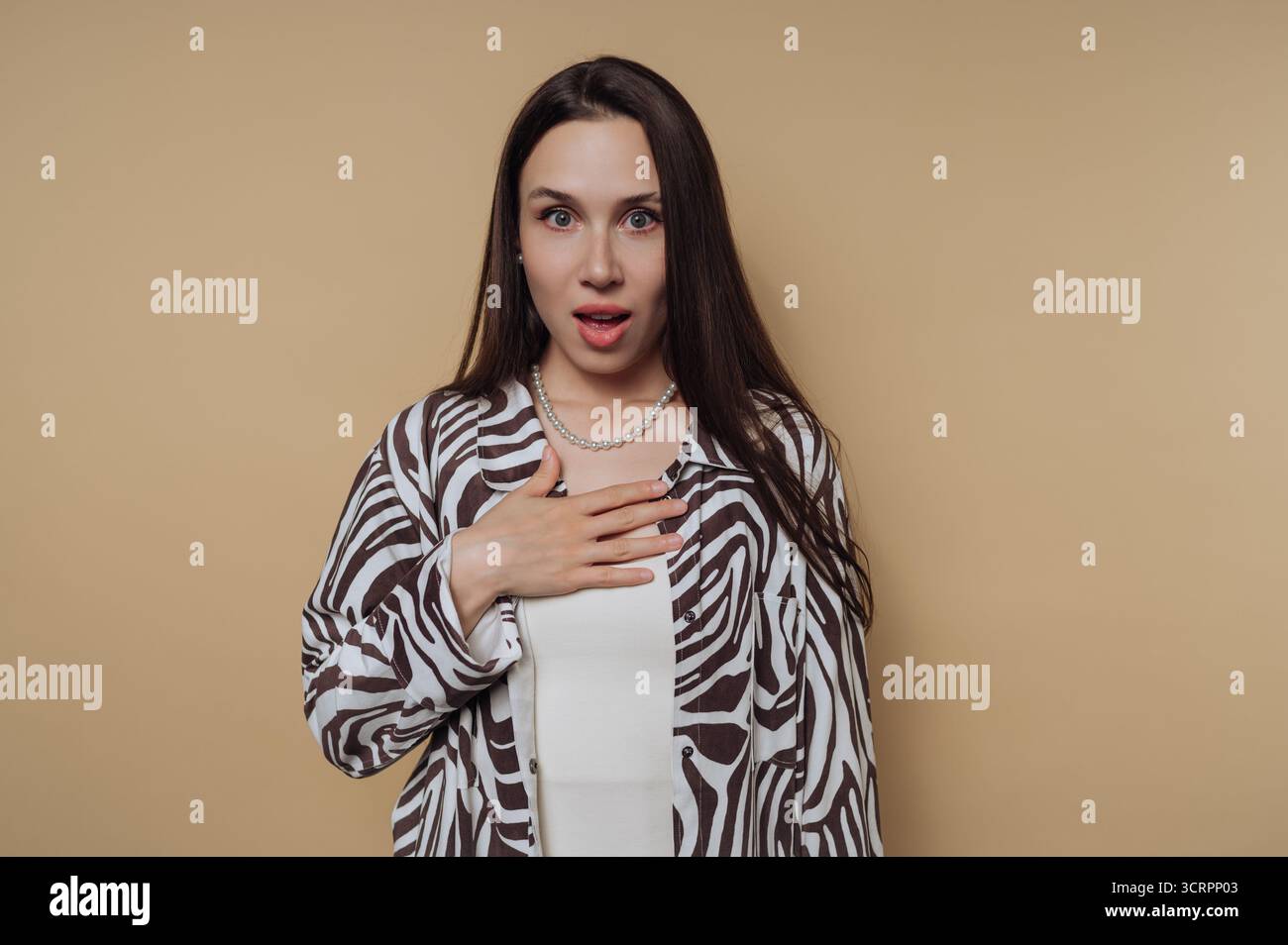Woman with surprised expression against beige background Stock Photo