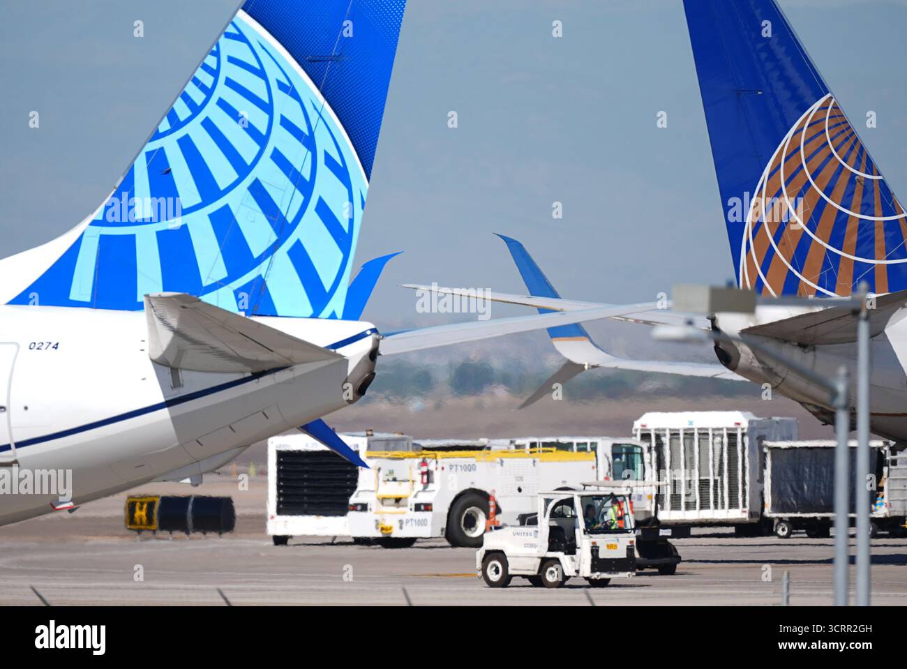 A ramp worker passes between the tail sections of a pair of United ...