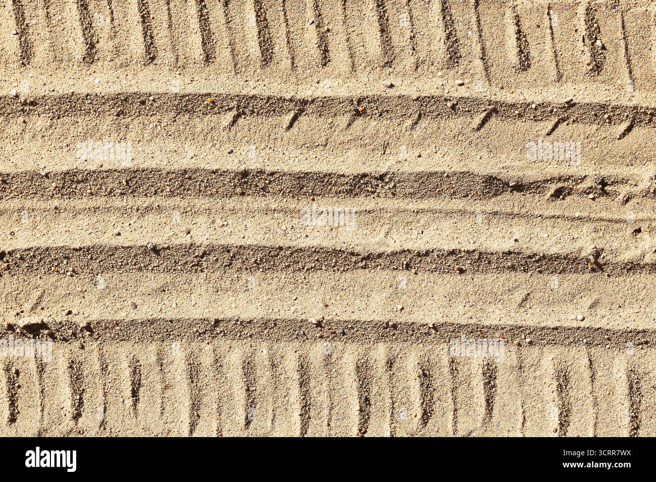 Tire tracks on sand surface. Offroad vehicle marks creating linear texture pattern. Outdoor travel and adventure background. Natural sandy ground. Stock Photo