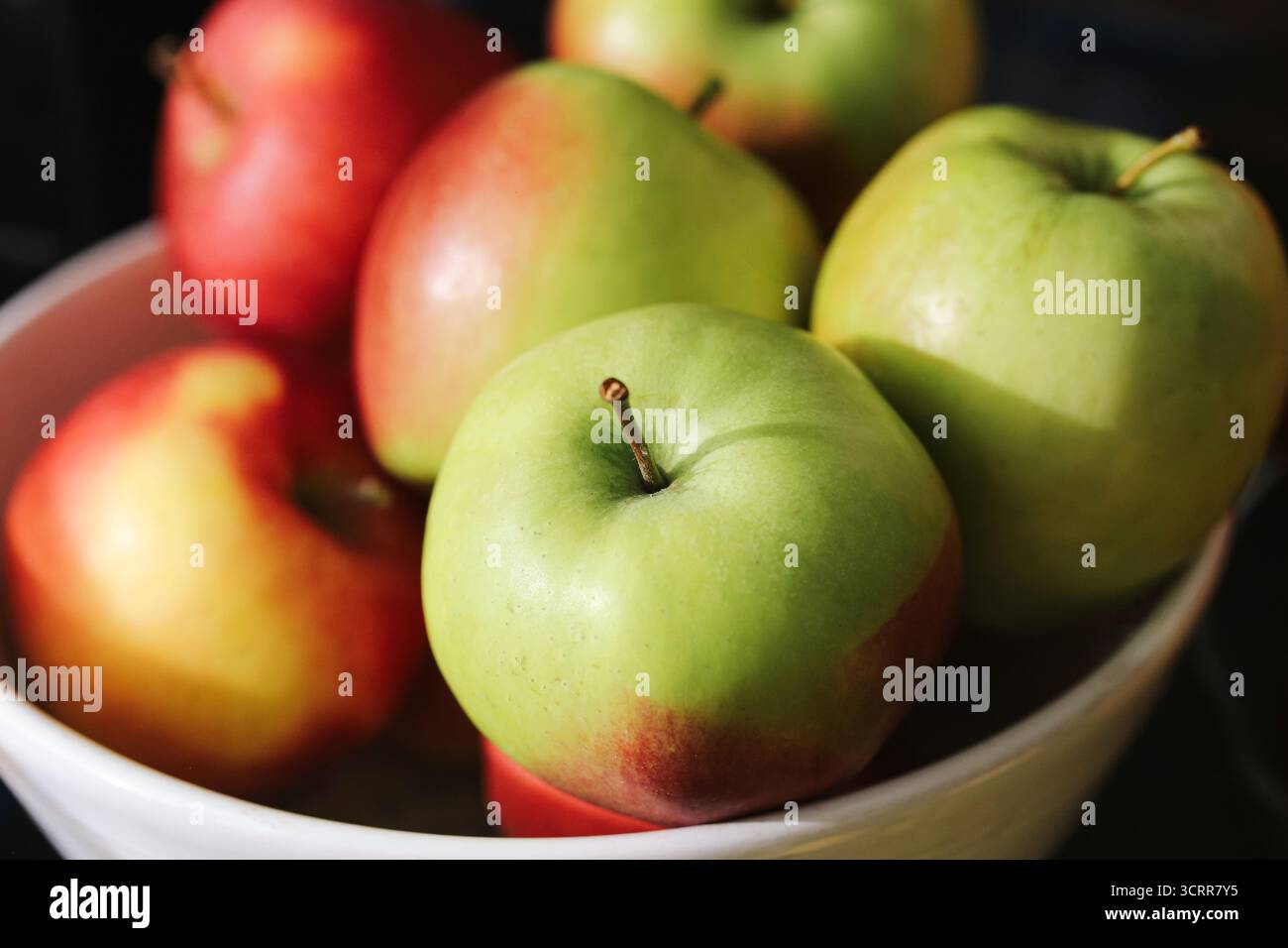 Fresh green and red apples in bowl. Natural fruit with organic skin and juicy texture. Healthy eating and vitamin food concept. Seasonal harvest. Stock Photo