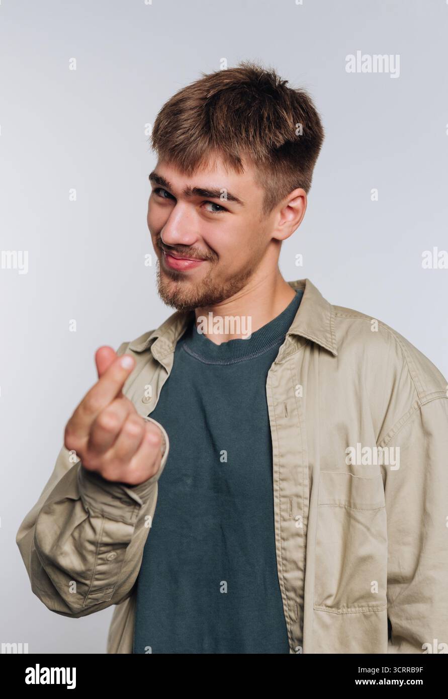 Young man making a finger heart gesture, smiling. Stock Photo