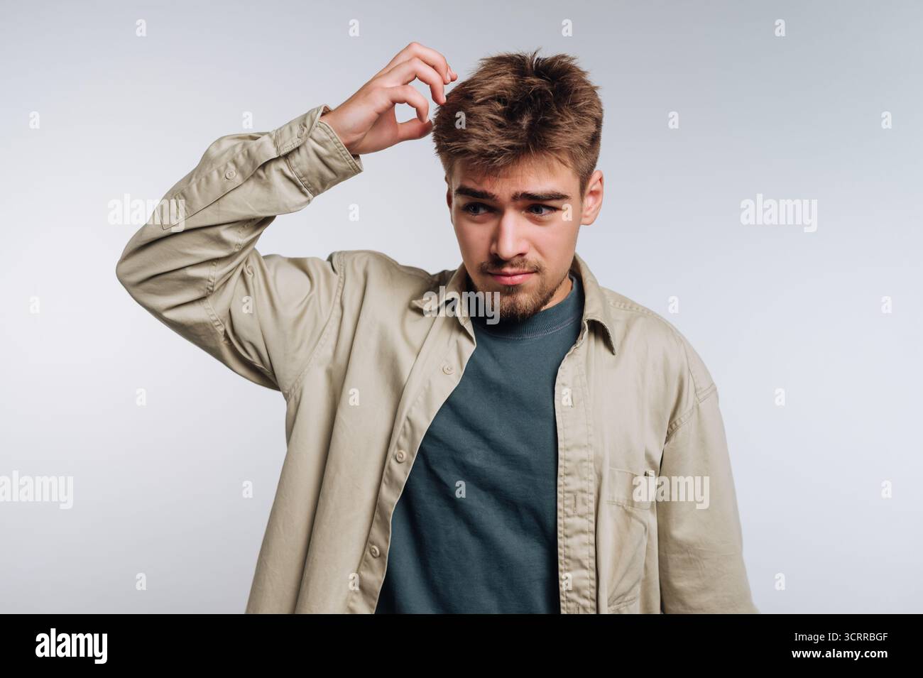 Young man scratching his head, looking confused. Stock Photo