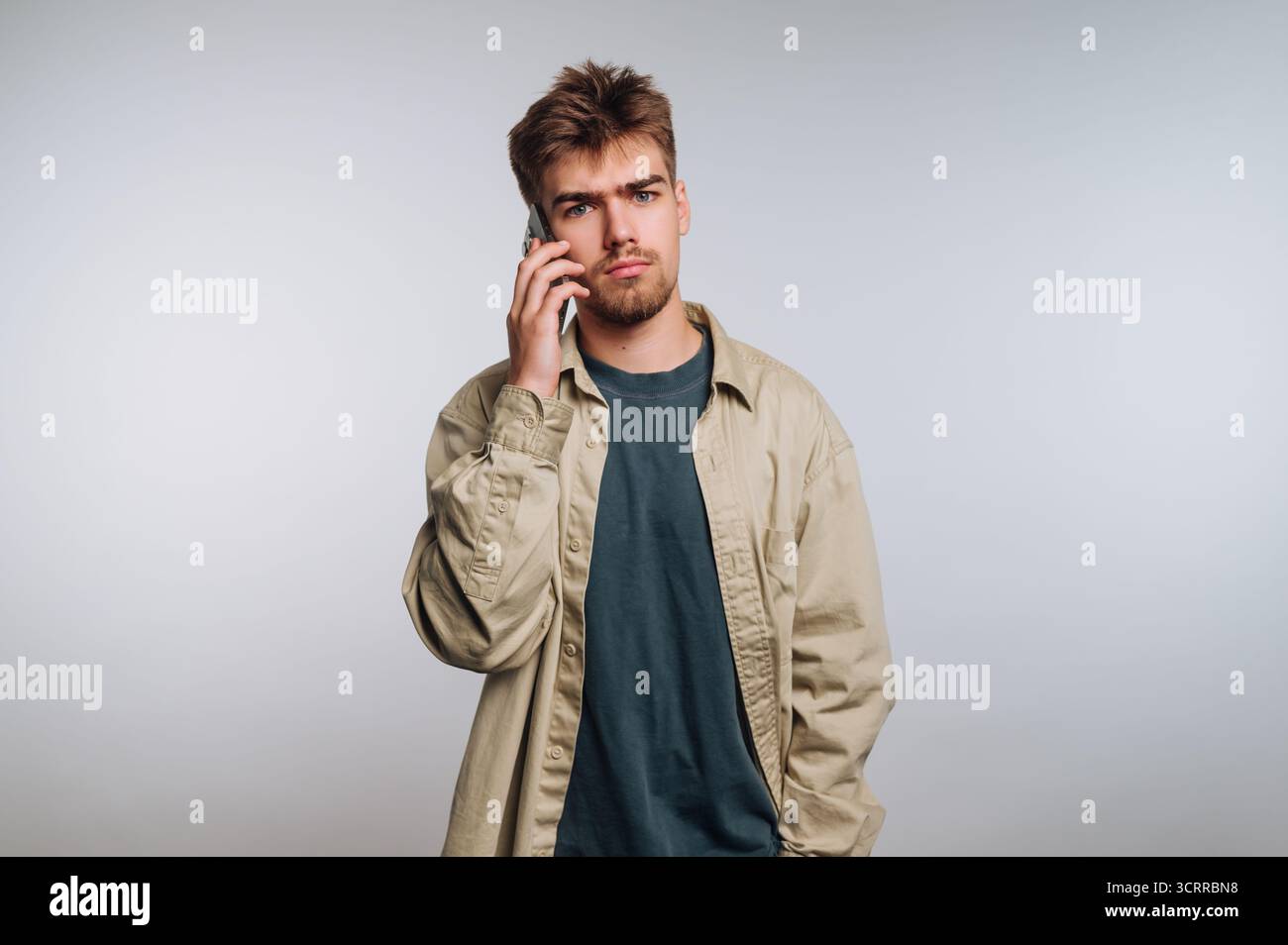 Young man with a serious expression talking on a smartphone. Stock Photo