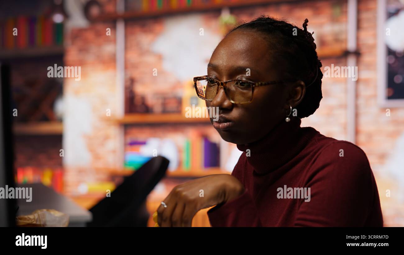 Programmer coding AI algorithm in startup, eating food at desk while refining machine learning models. Stressed woman using coding platform in Silicon Valley office and enjoying snack, camera B Stock Photo