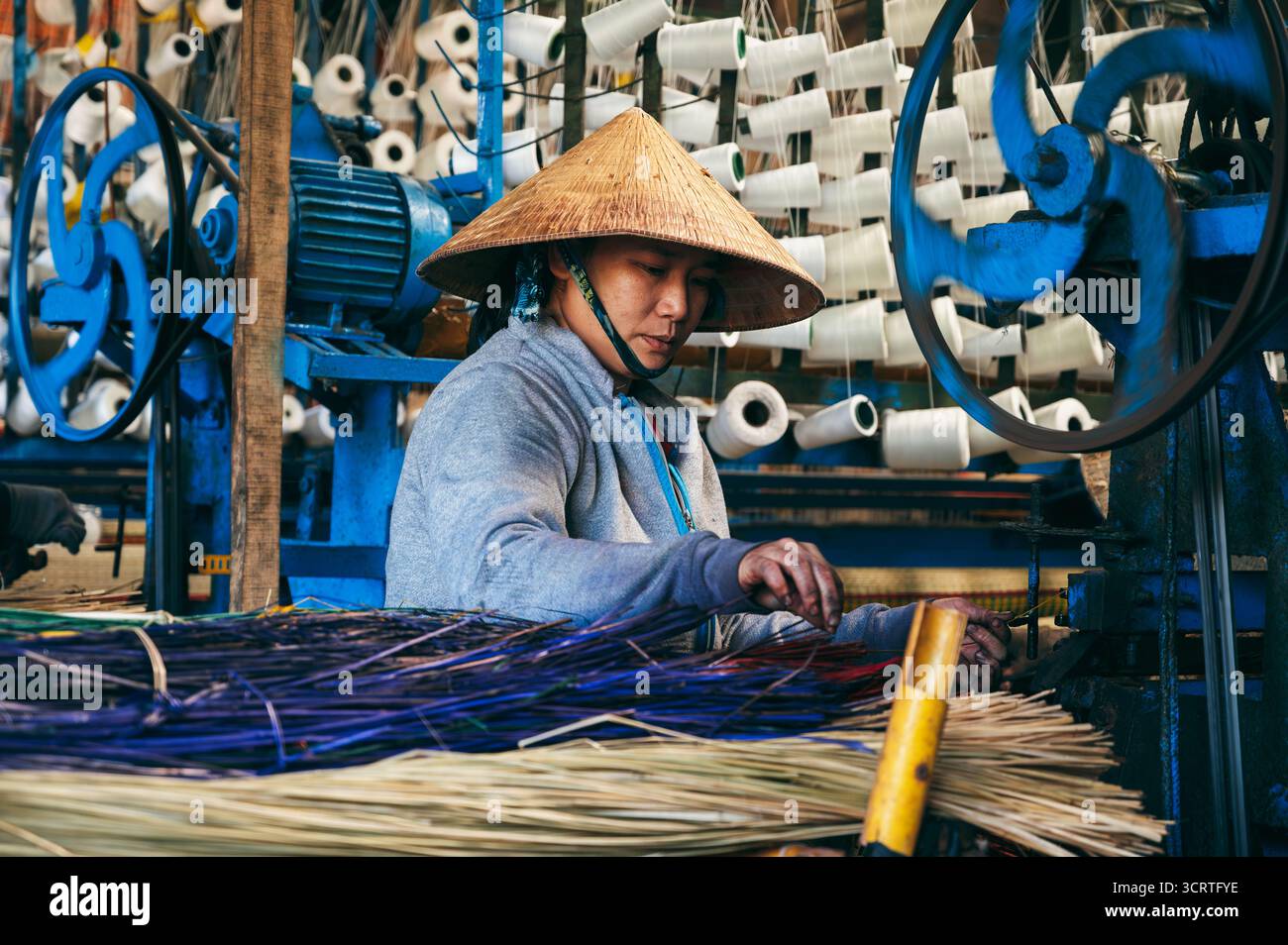 Local Weaving Machine Vietnamese woman weaver in a straw hat works at a loom weaving machines ...