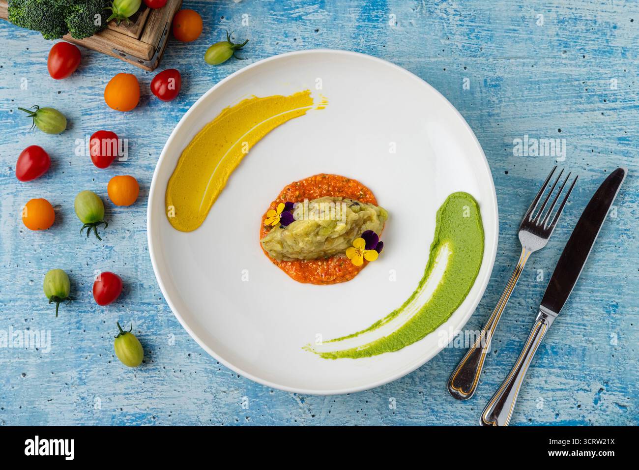 Eggplant puree with colorful sauces and edible flower garnish Stock Photo
