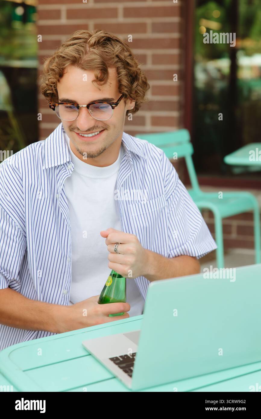 Young man smiling working on laptop relaxing outdoors Stock Photo