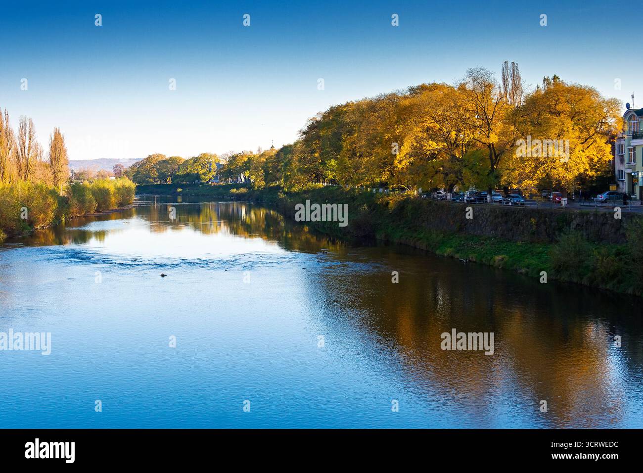 uzhhorod, ukraine - 31 oct, 2010: embankment of the river Uzh in autumn. beautiful view of old city with colorful foliage on trees in evening light. s Stock Photo