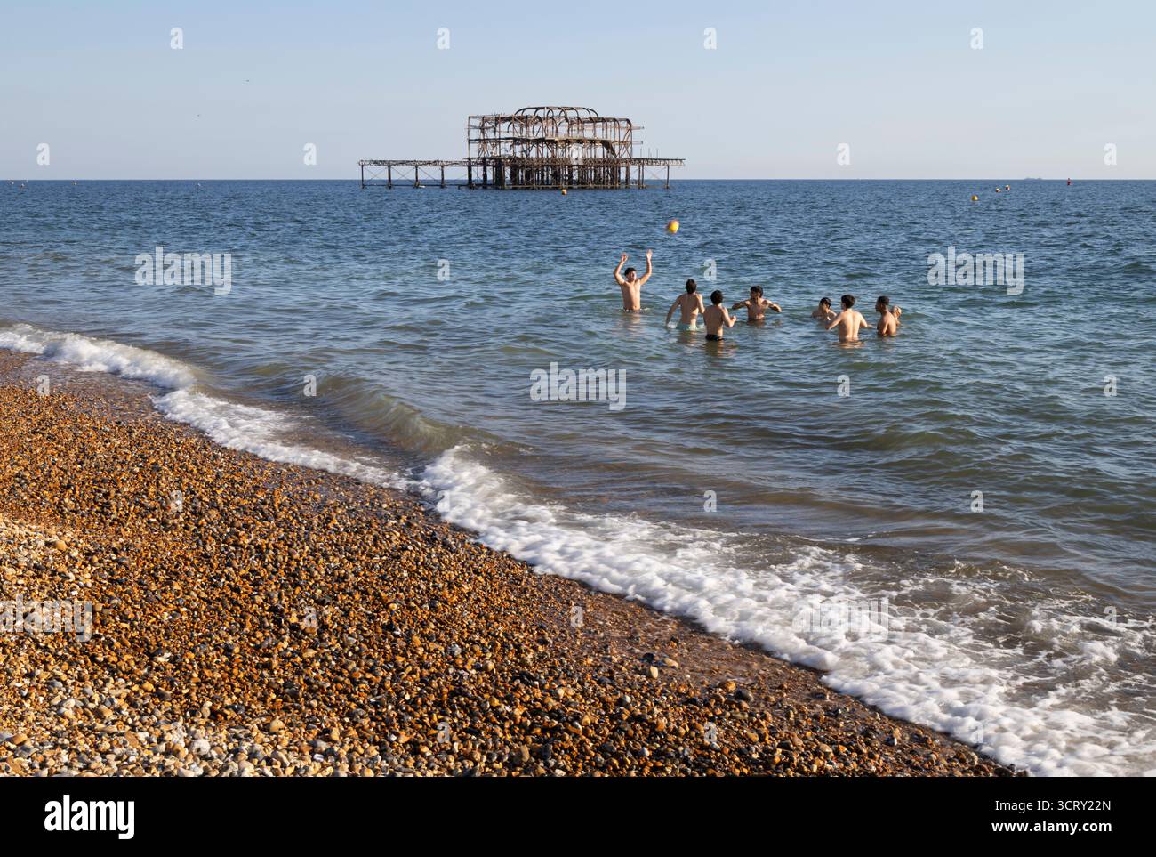 Group of young men playing in the sea with Brighton West Pier behind, Brighton, East Sussex, England, United Kingdom, Europe Stock Photo